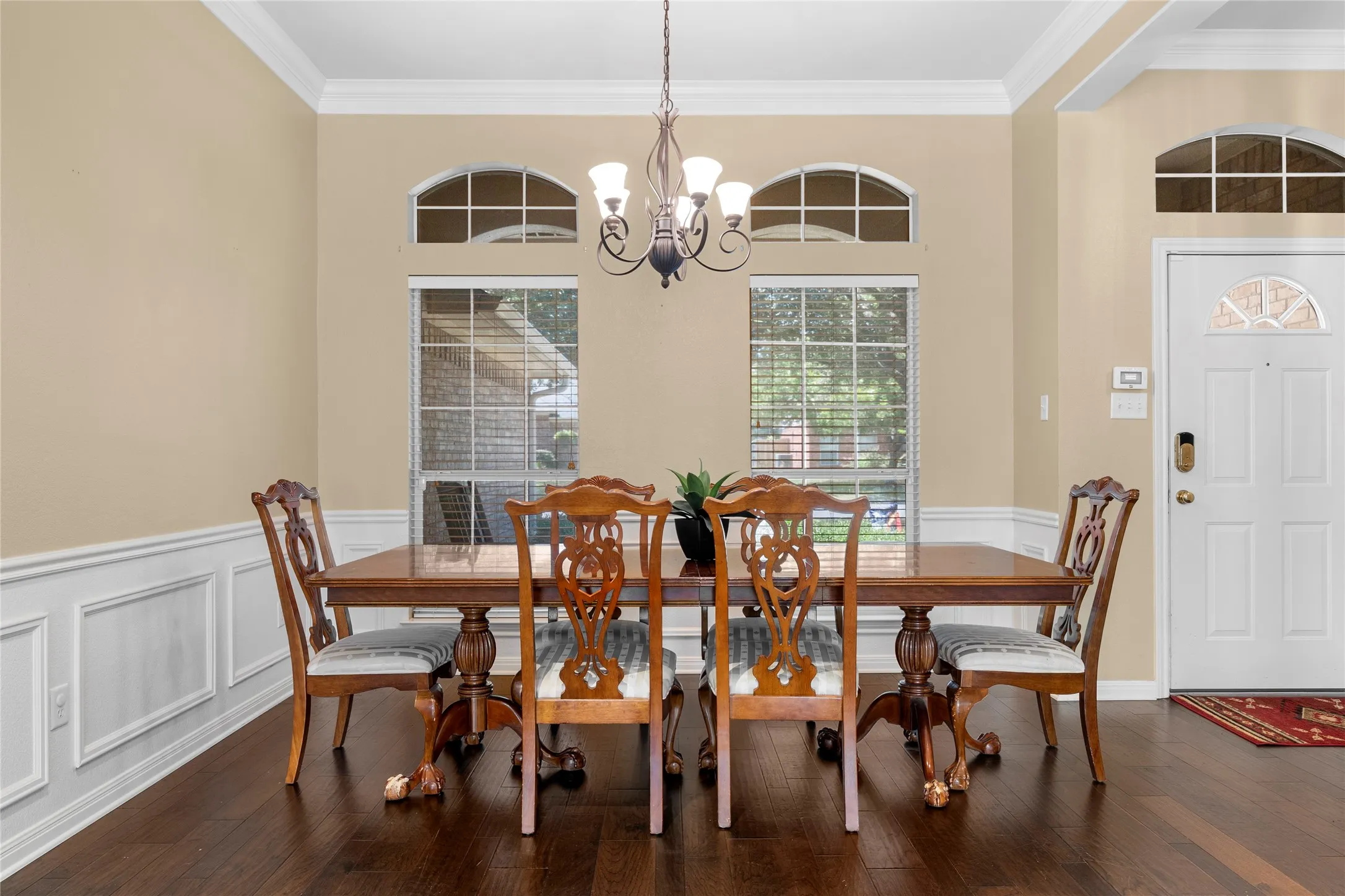 Hardwood-finish flooring, crown molding, wainscoting, arched transom windows, and a chandelier
