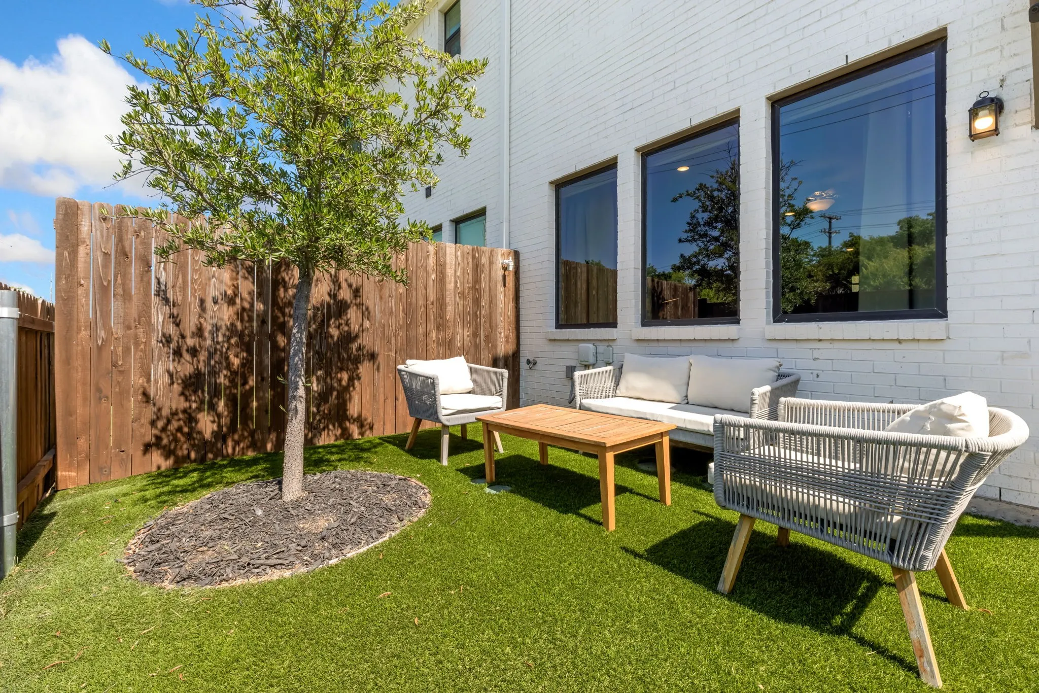Private outdoor space featuring artificial turf, a mature tree, and a wood privacy fence