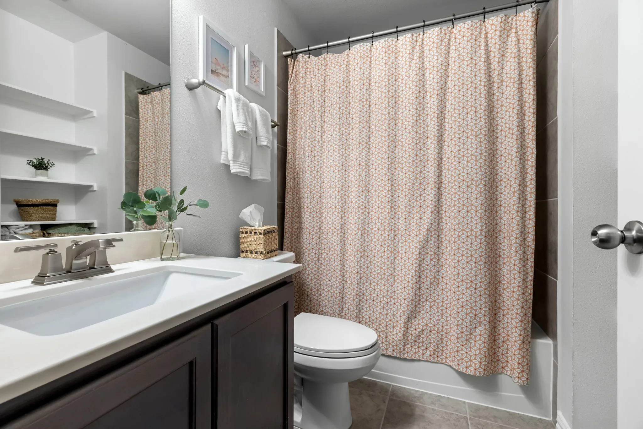 Bathroom featuring a dark wood-finish vanity with an integrated sink, brushed nickel faucet, and white countertop