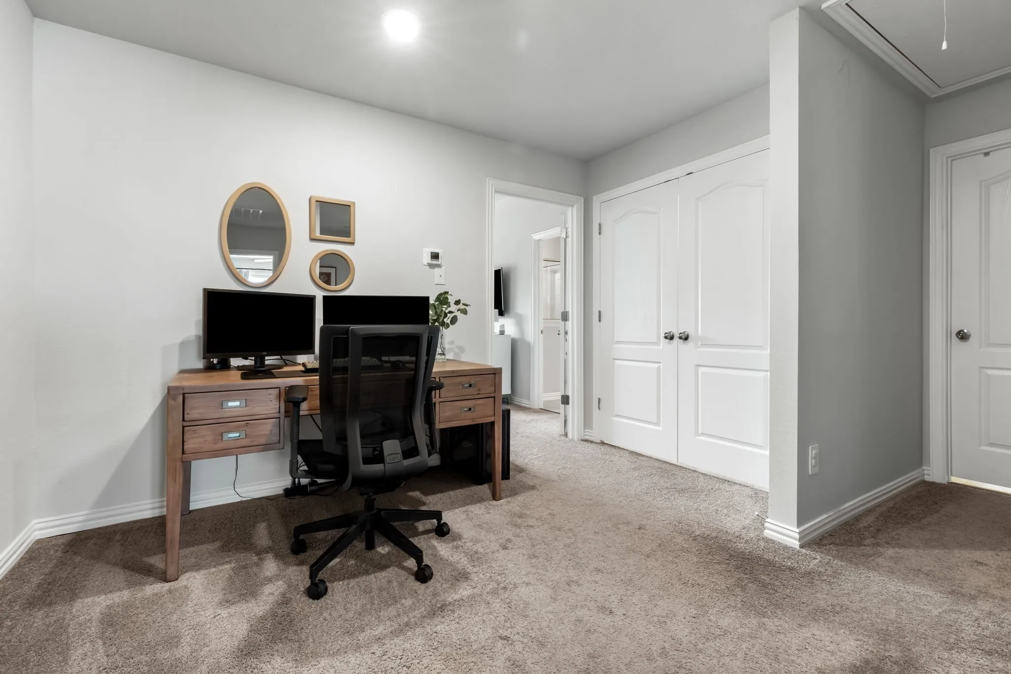 Dedicated home office featuring a wood-finish desk with storage drawers, ergonomic seating, and integrated shelving