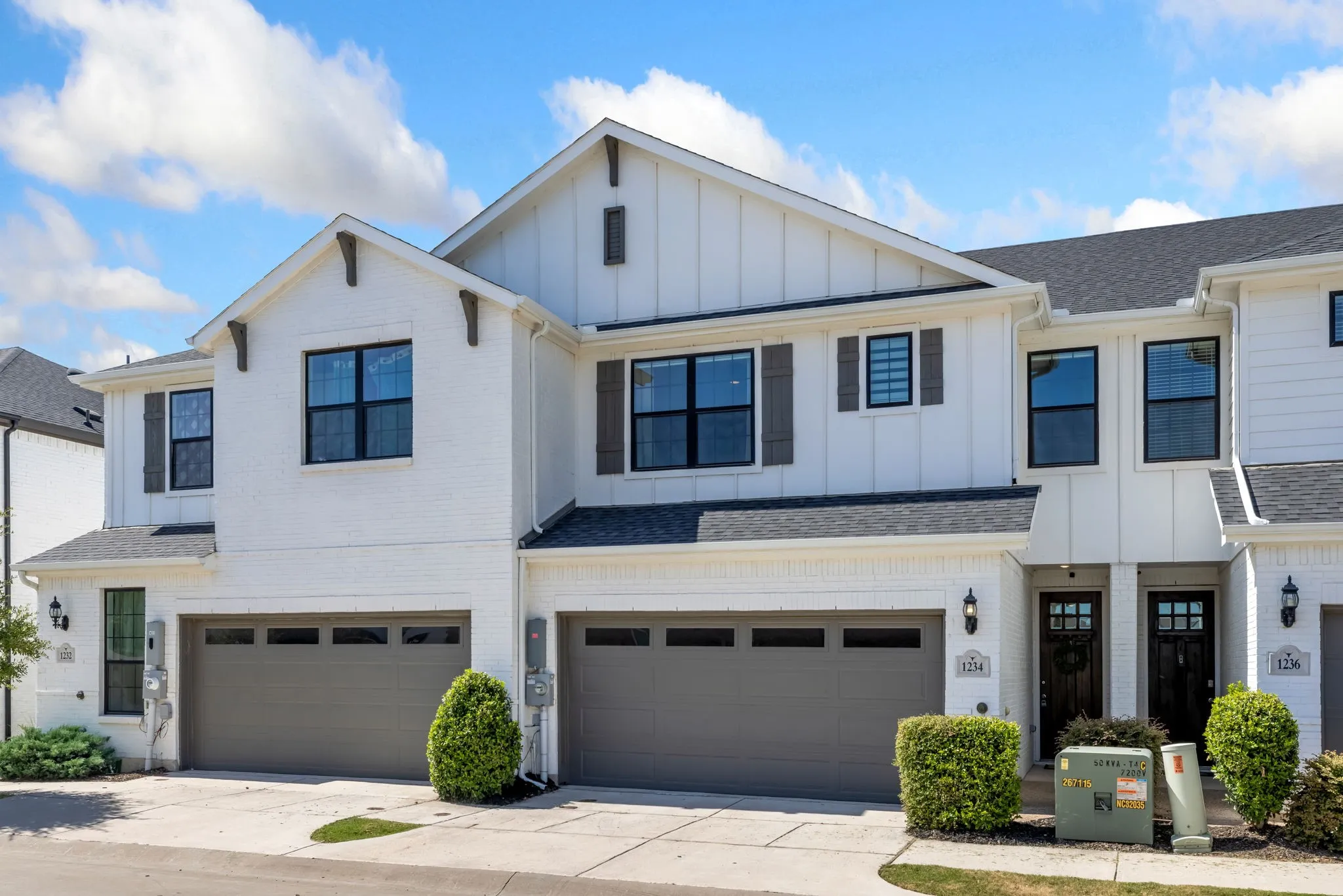 White brick exterior with board and batten accents, dark-frame windows, and dark shutters