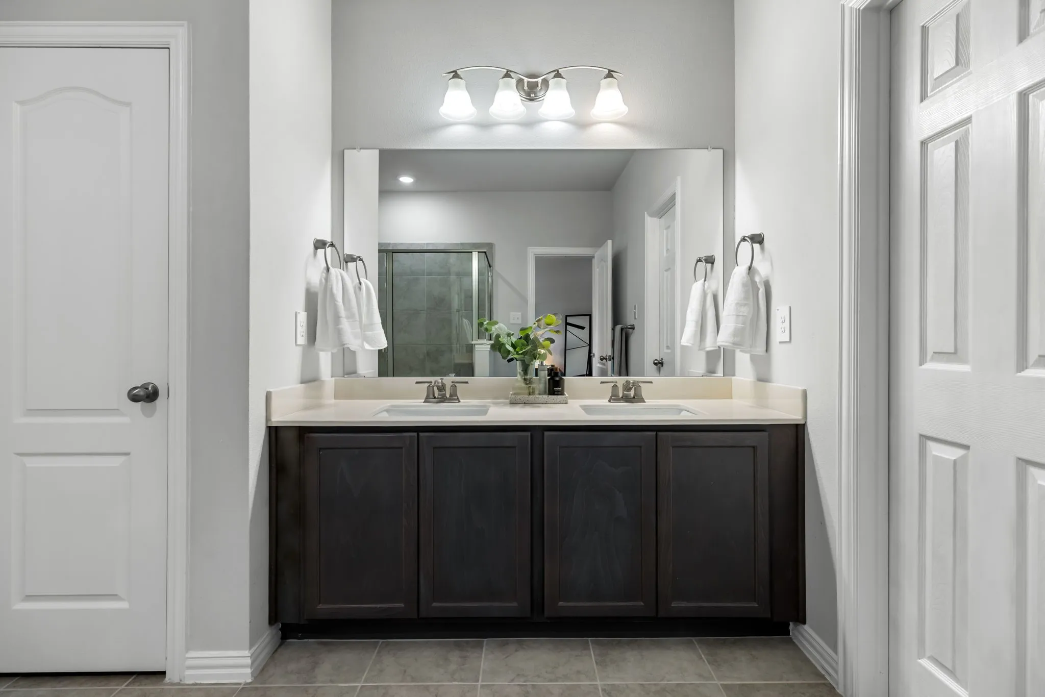 Spa-inspired primary bathroom featuring a double-sink vanity with a quartz countertop, matte black cabinetry, and polished nickel fixtures
