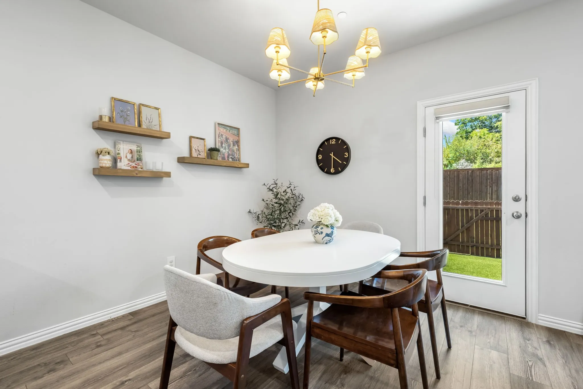 Bright dining area with round white table, wood-finish flooring, and mid-century modern seating
