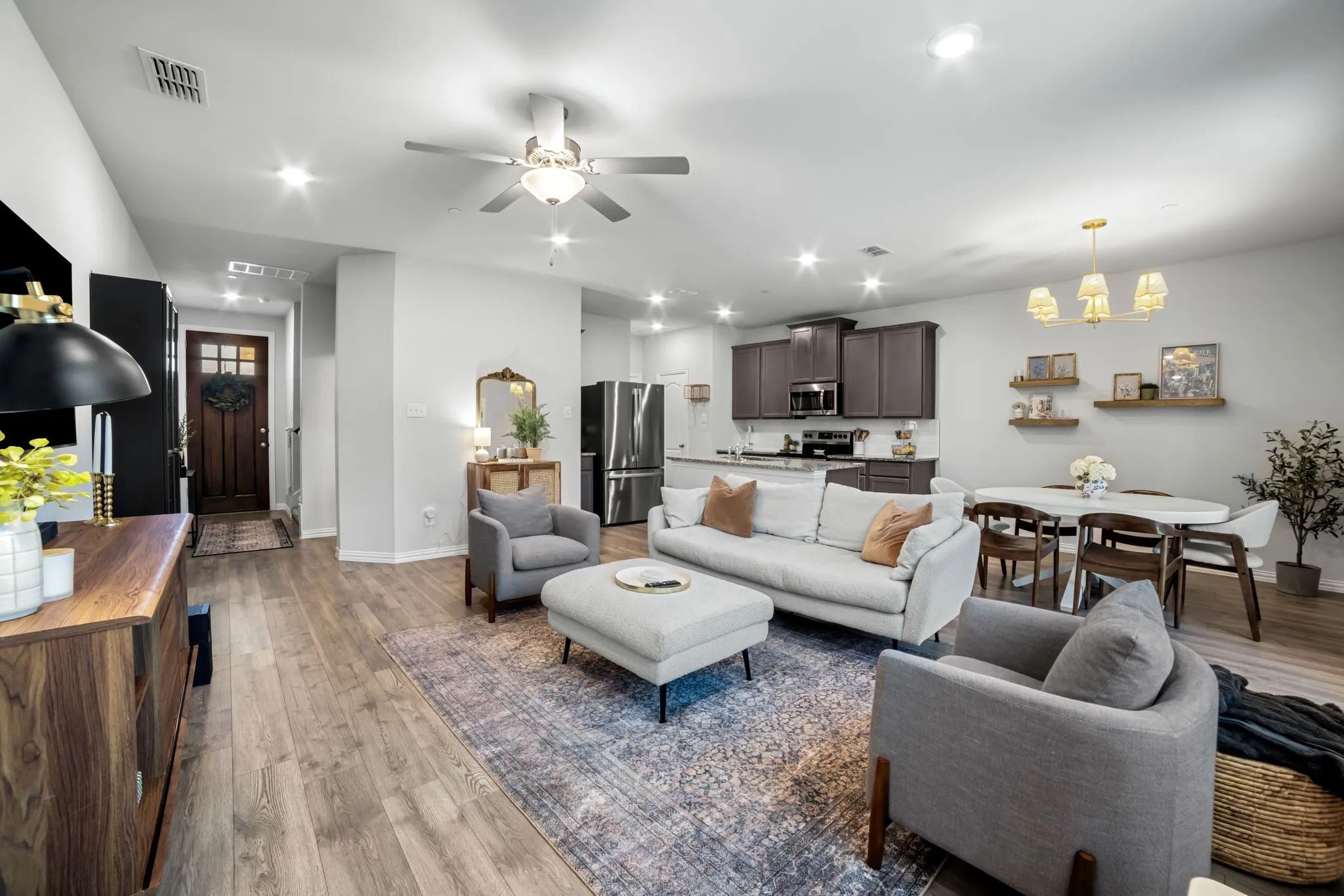Open-concept living area featuring a wood-finish plank floor, recessed and ceiling fan lighting, and a neutral color palette