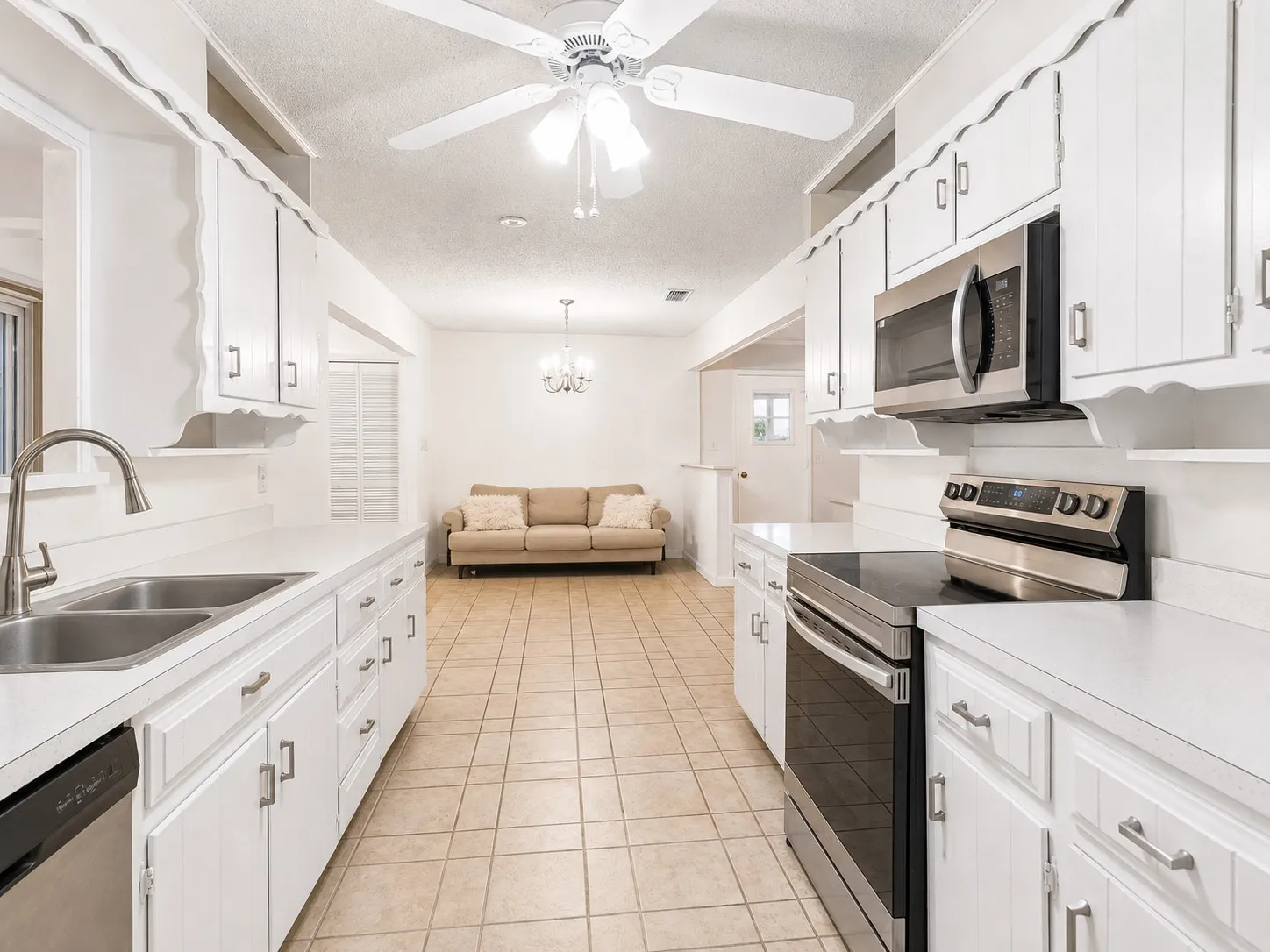 White cabinetry with decorative trim, stainless steel appliances, dual basin sink with pull-down faucet, and tile flooring