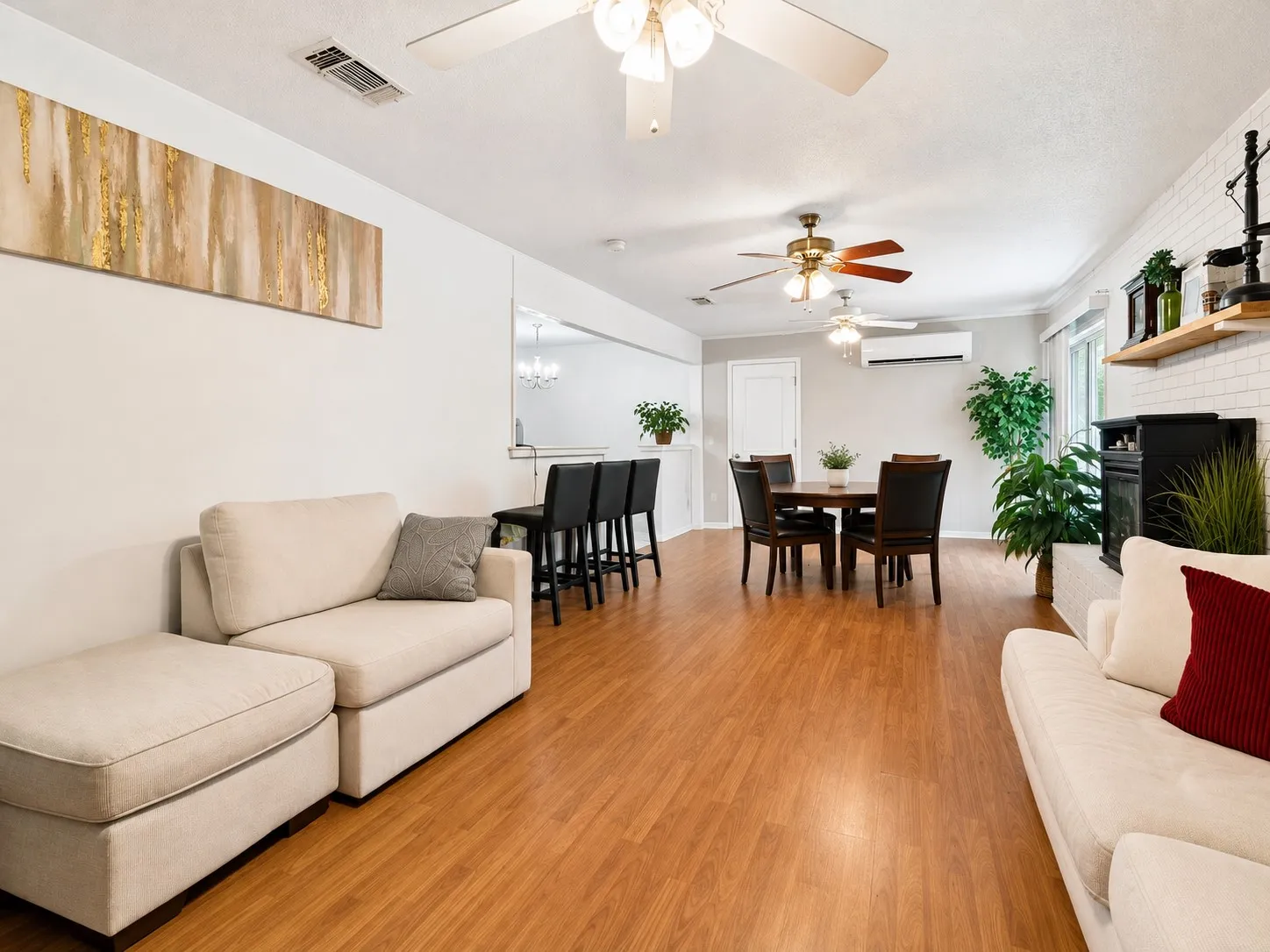 Wood-finish flooring throughout, white painted walls, and a fireplace with white brick surround