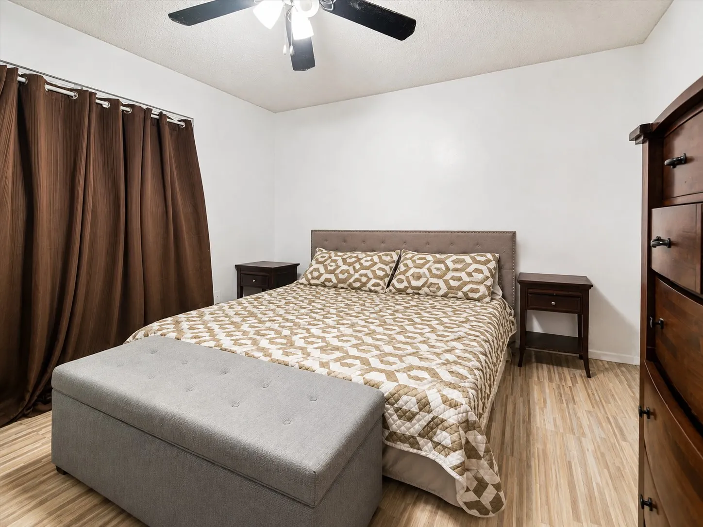 Ceiling fan with integrated lighting, window with curtain rod, wood-finish flooring, white walls