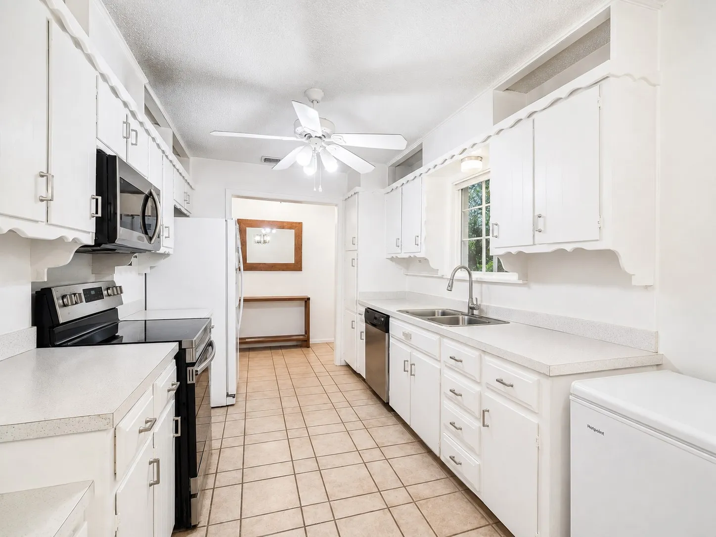 Galley kitchen featuring white cabinetry, light-toned countertops, and tile flooring