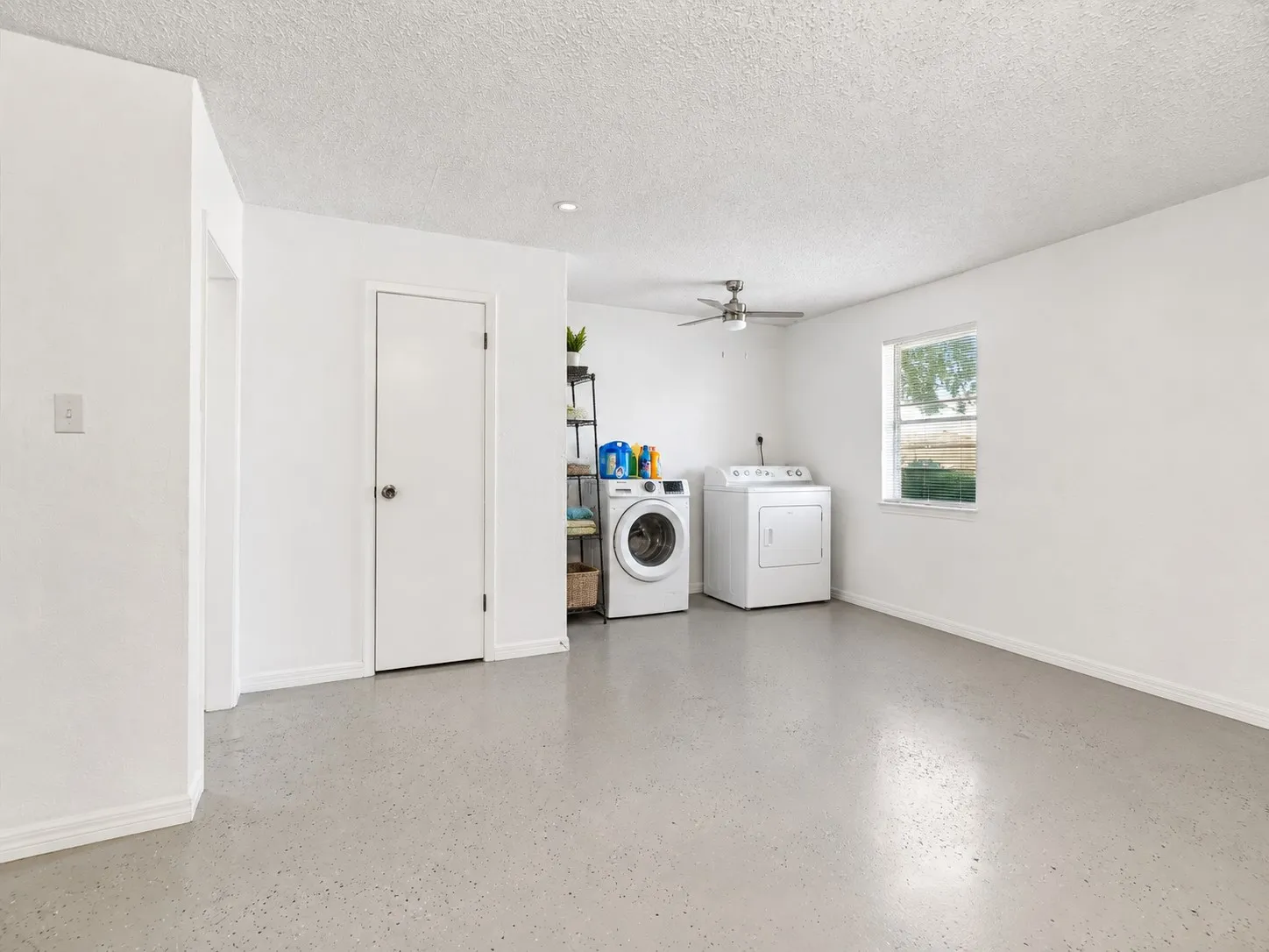 Spacious utility room with light-toned flooring, white walls, and a ceiling fan