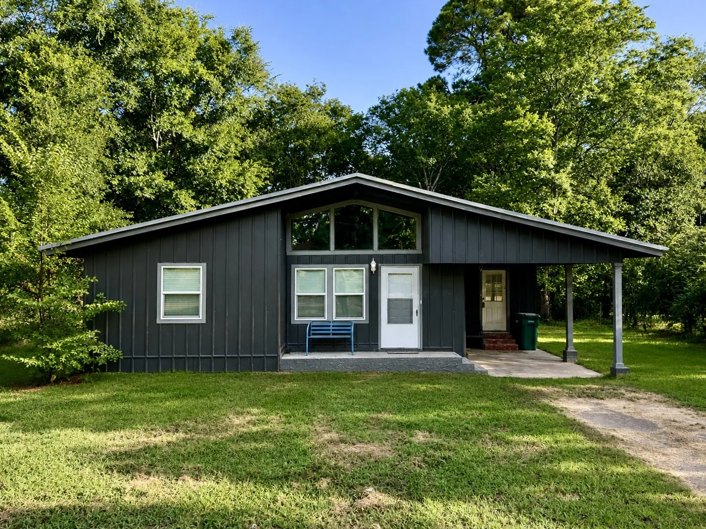 Vertical panel siding with a covered entry, gabled roofline, and multiple windows