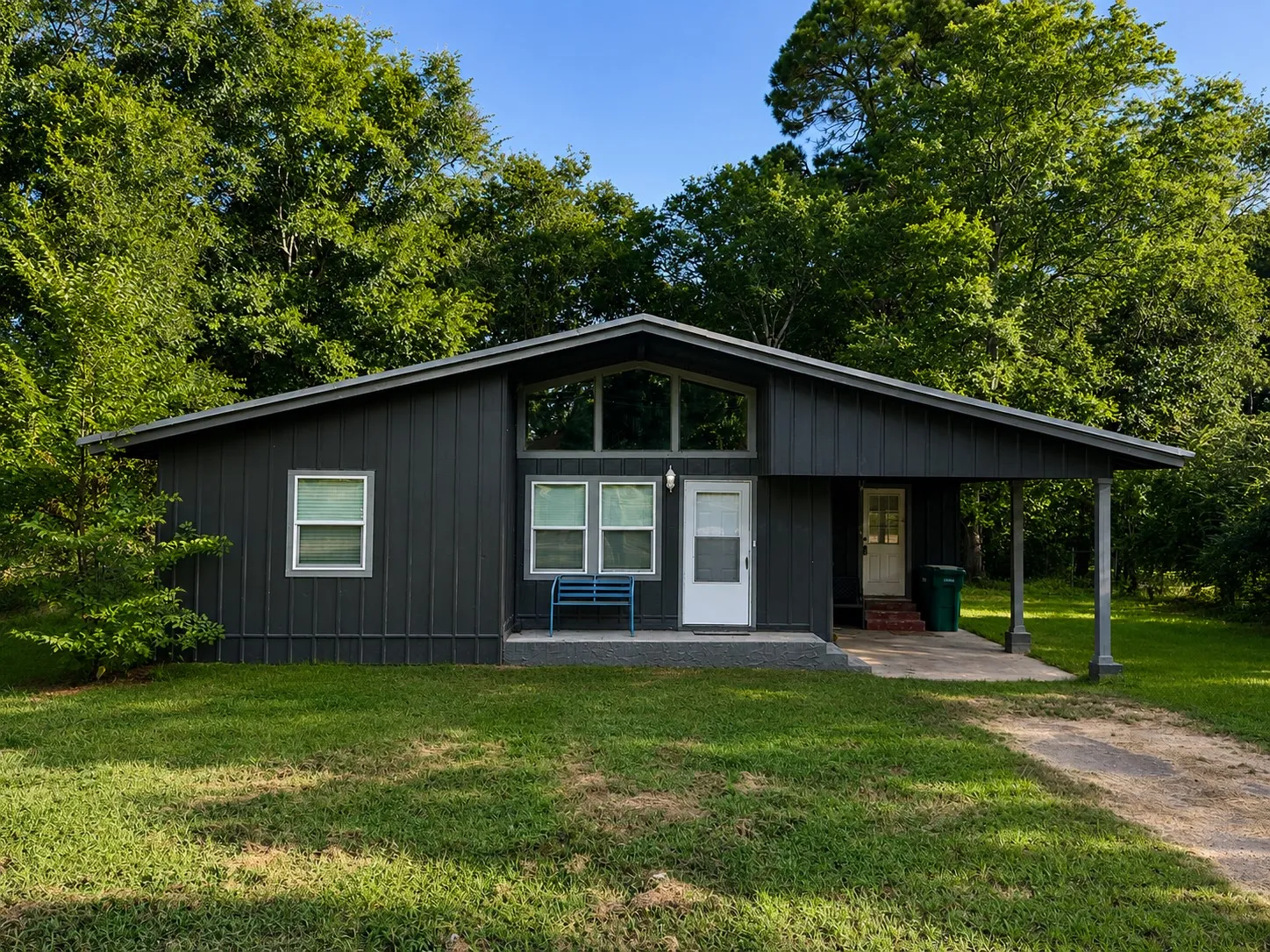 Modern black metal-sided residence featuring a pitched roof design, expansive front-facing windows, and a covered entry porch