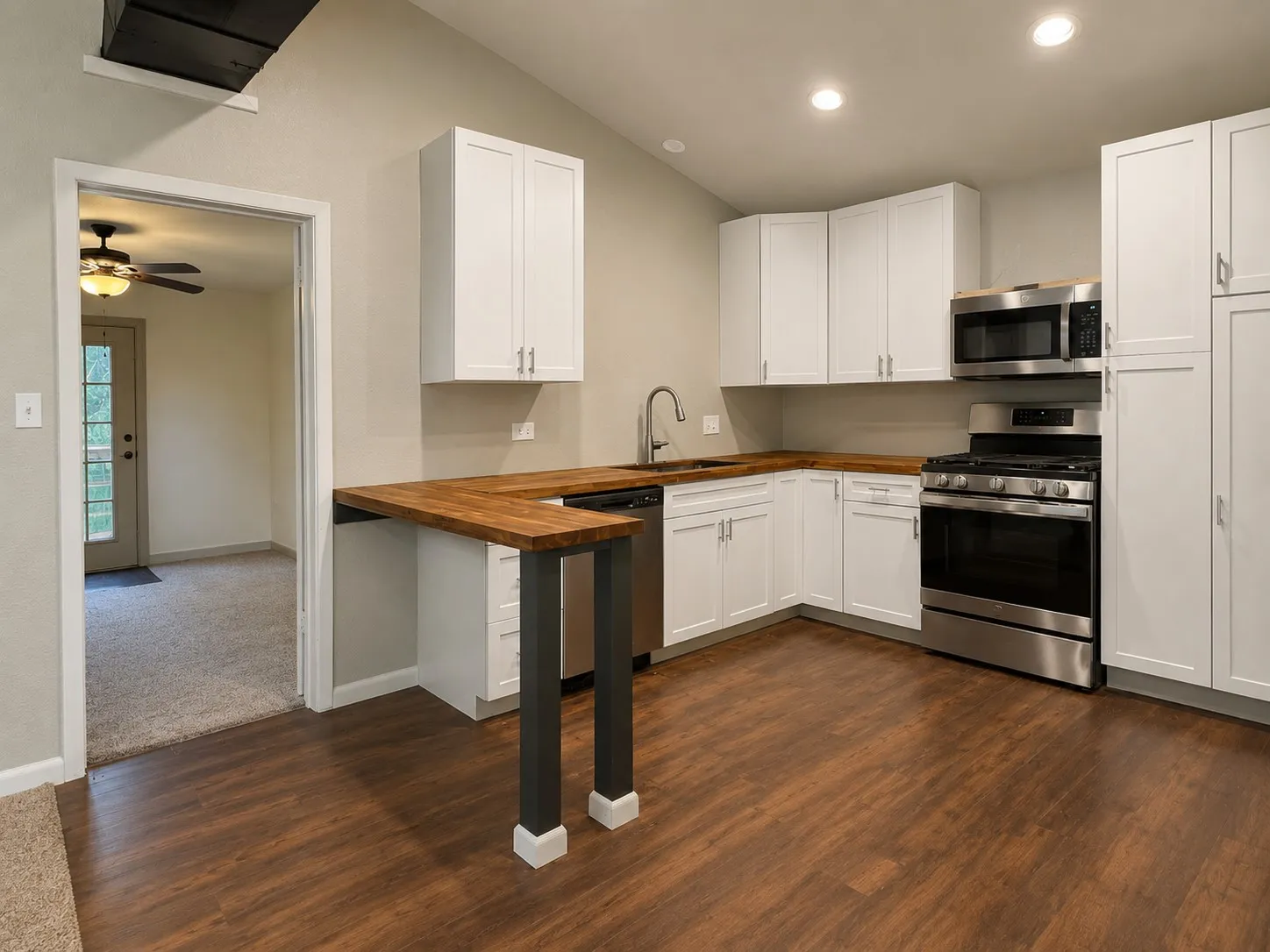 Modern kitchen featuring crisp white cabinetry with stainless steel appliances, including a gas range and built-in microwave