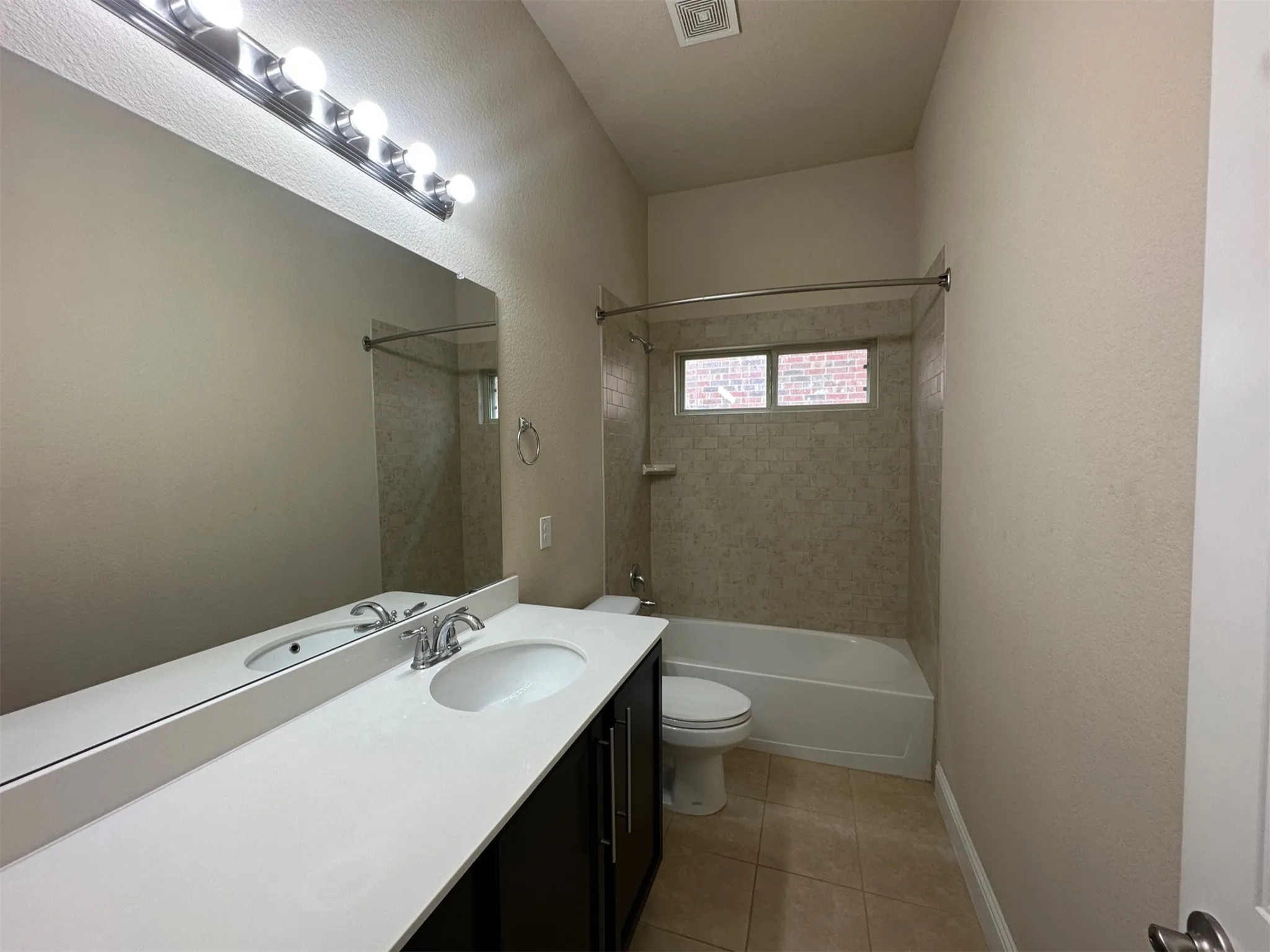 Bathroom featuring a spacious vanity with an undermount sink, a large mirror, and overhead strip lighting