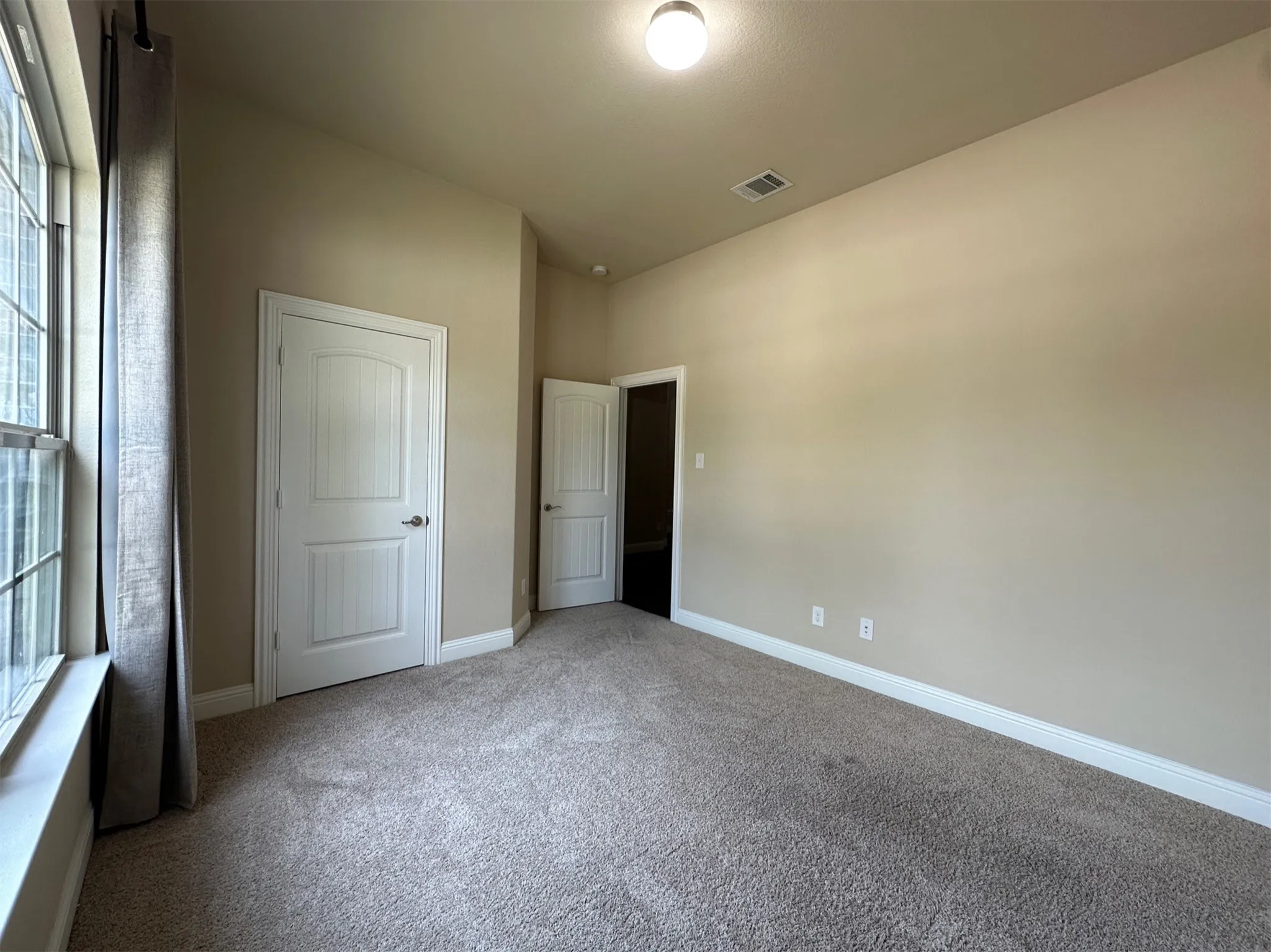 Spacious room featuring neutral paint, light-colored carpet flooring, and white trim