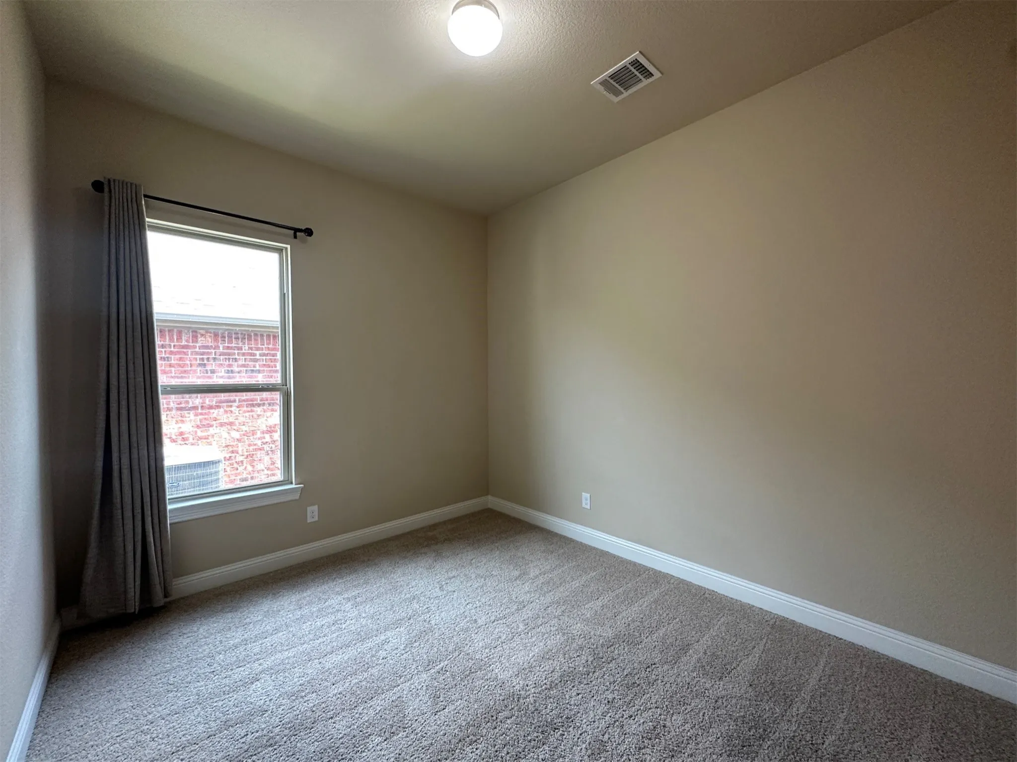 Neutral-toned room with plush carpeting and a single window