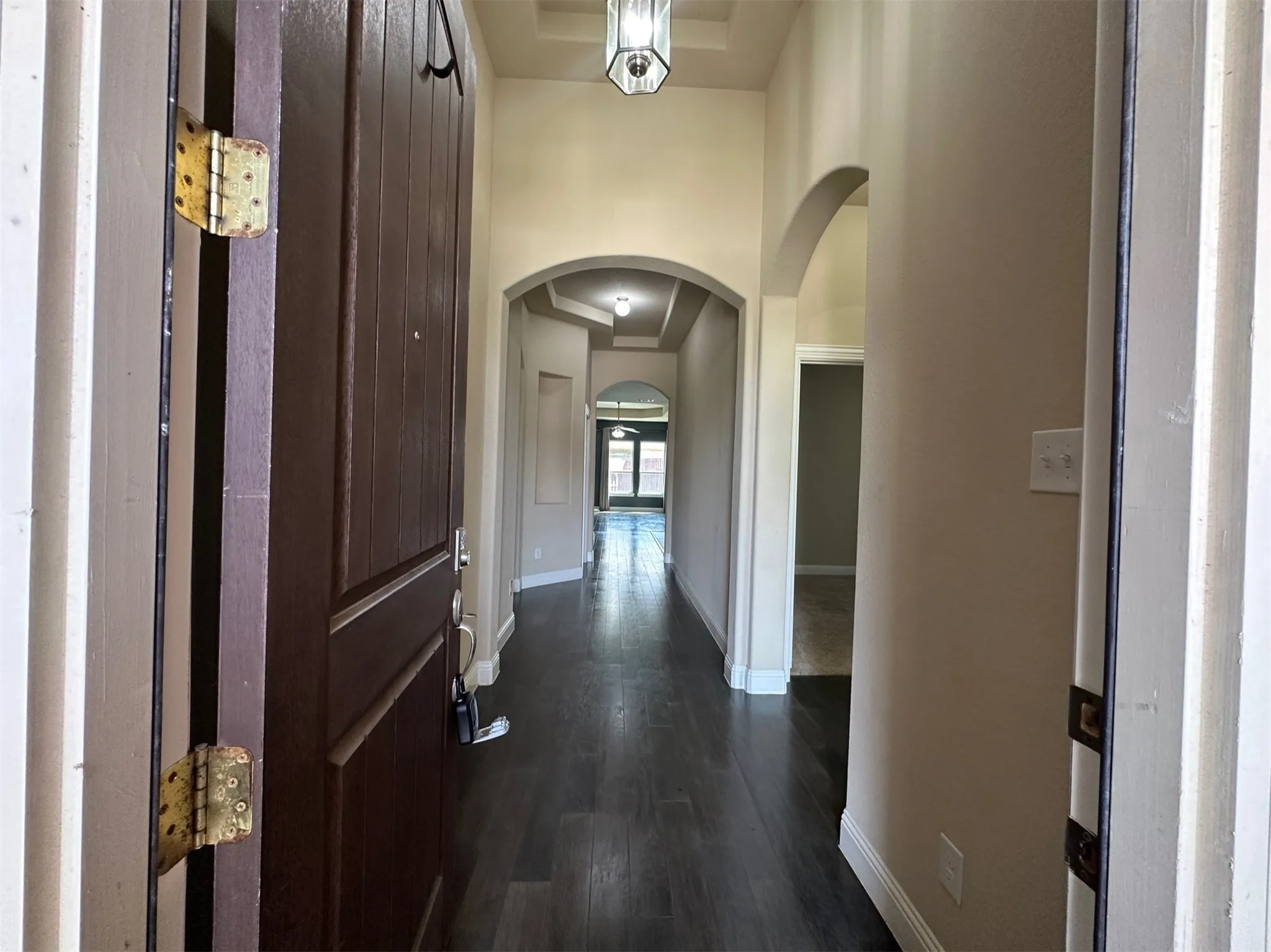 Entryway featuring dark wood-finish flooring, light neutral wall paint, and arched architectural details