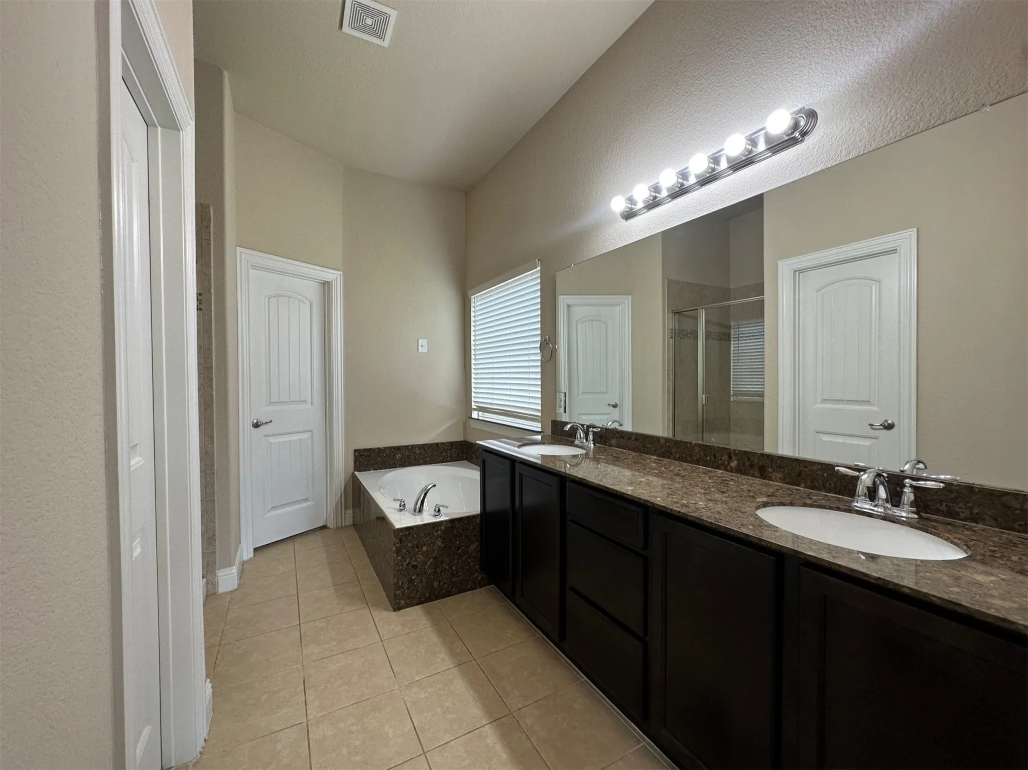 Bathroom featuring a double vanity with dark wood cabinetry, integrated sinks, and a stone-finish countertop