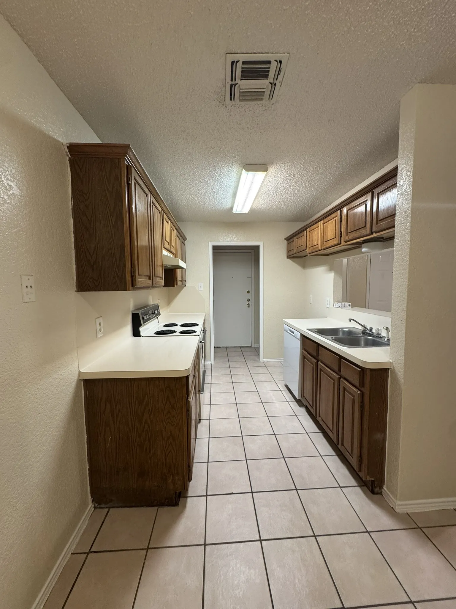 Galley kitchen featuring wood-finish cabinetry, tile flooring, and a white electric range