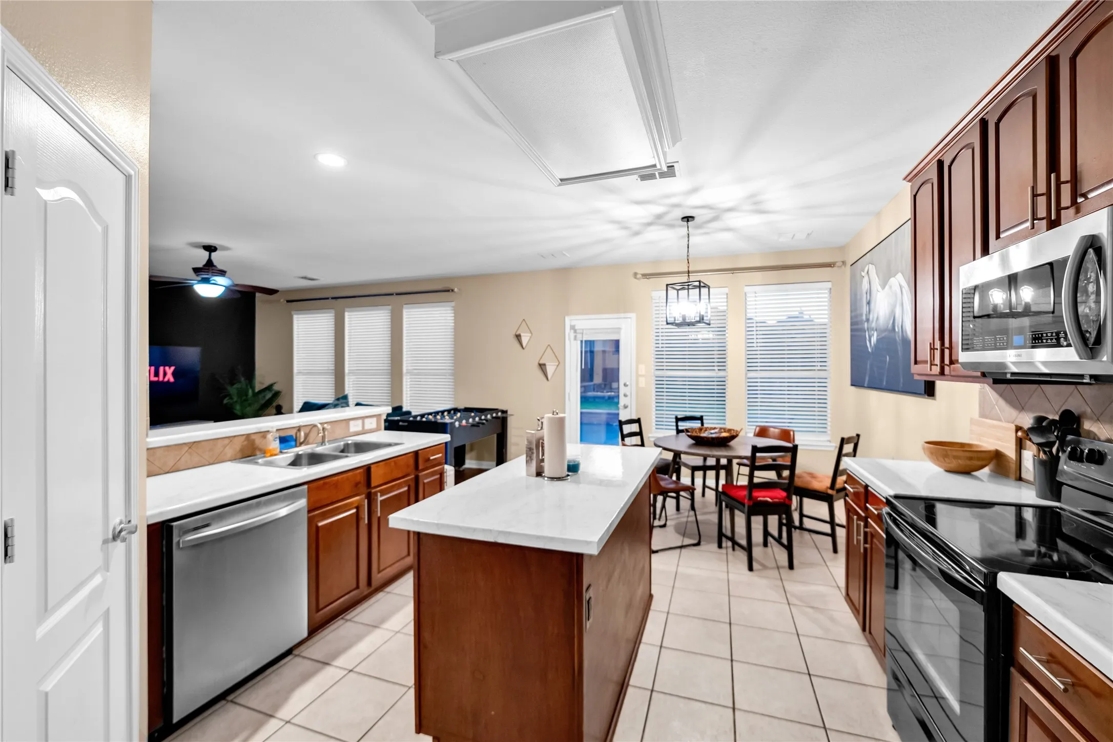 Kitchen featuring a built-in microwave, stainless steel dishwasher, white countertops, and tile flooring