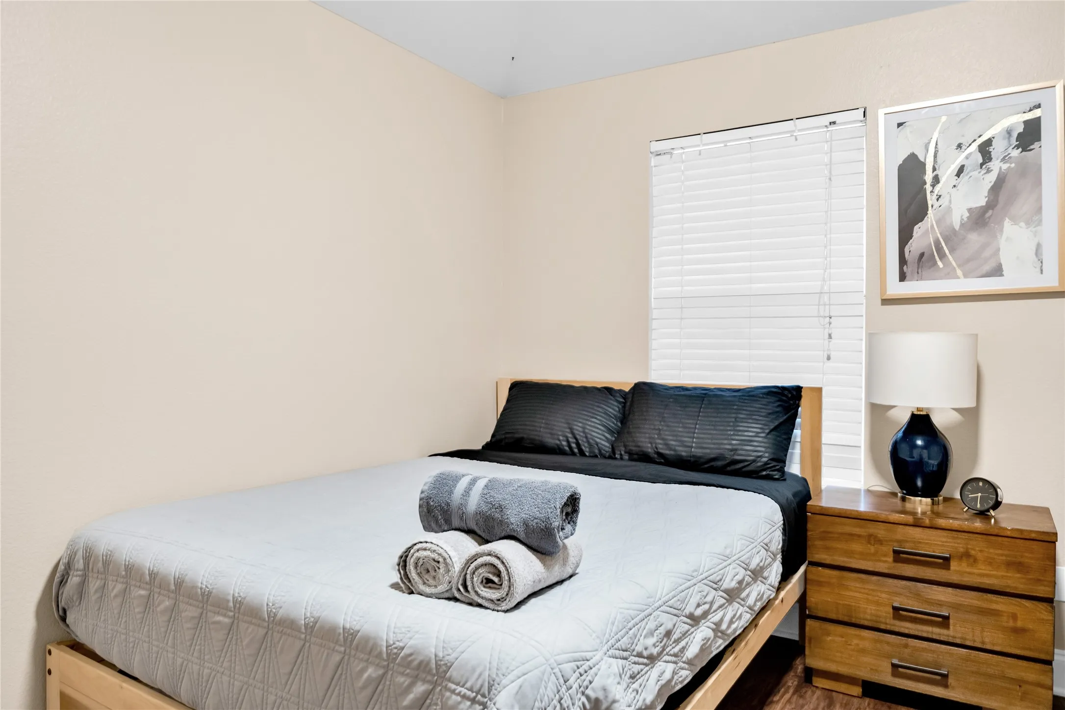 Wood-finish flooring, neutral wall tones, and a window with horizontal blinds