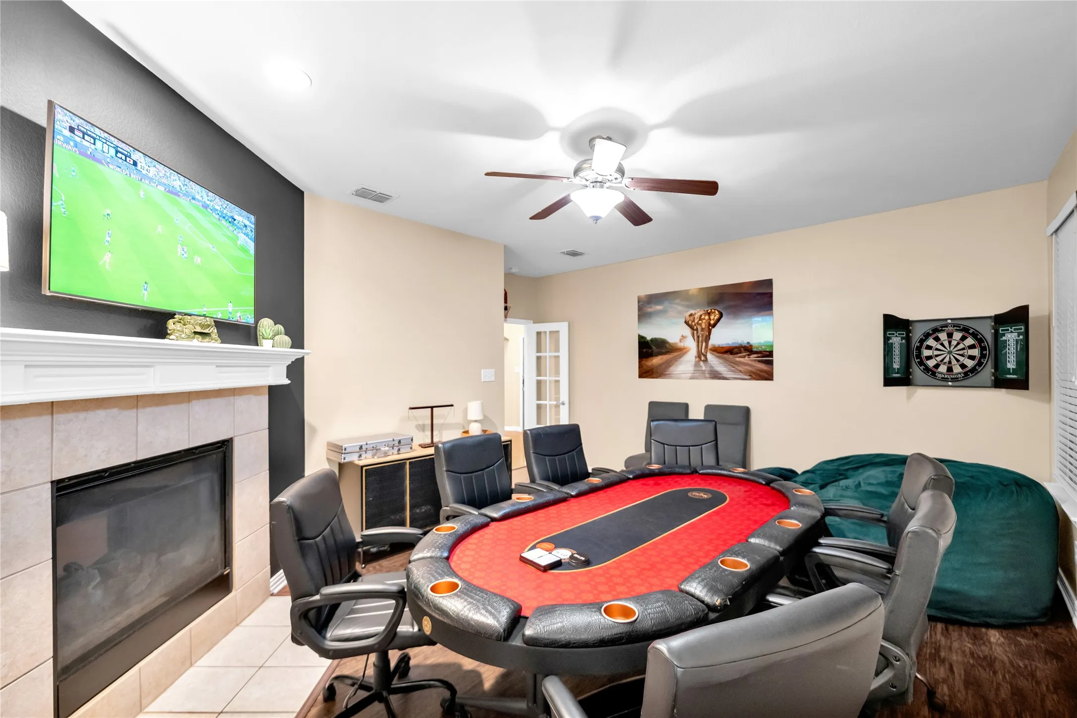Fireplace with tile surround, wood-finish flooring, and ceiling fan