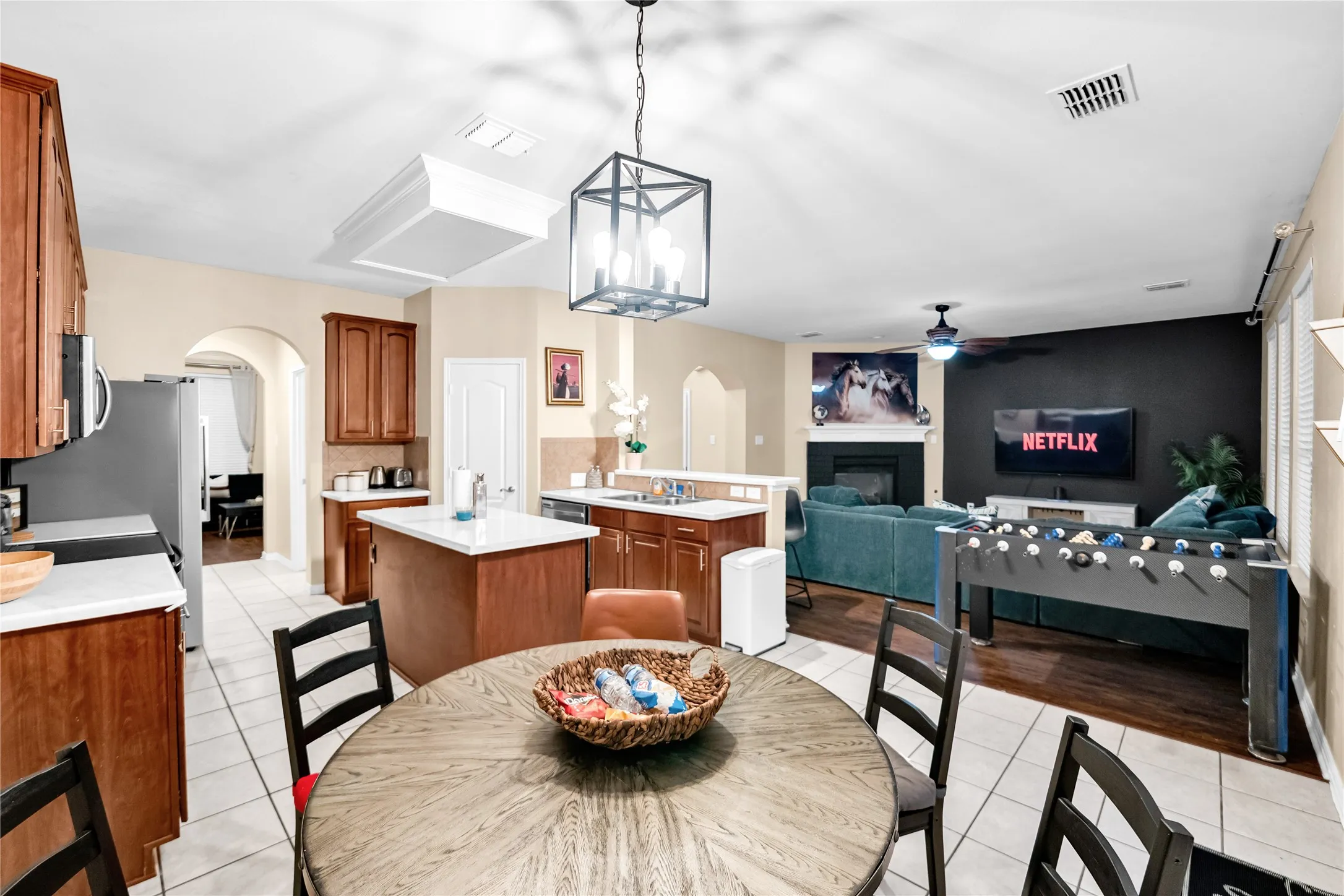 Open-concept living space featuring a kitchen with a center island, wood cabinetry, and stainless steel appliances