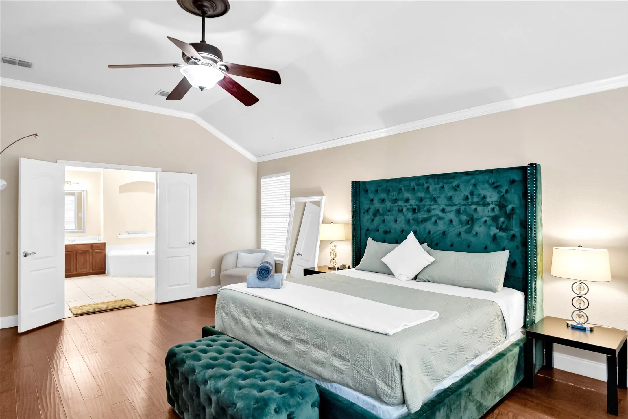 Vaulted ceiling with crown molding, wood-finish flooring, and a ceiling fan