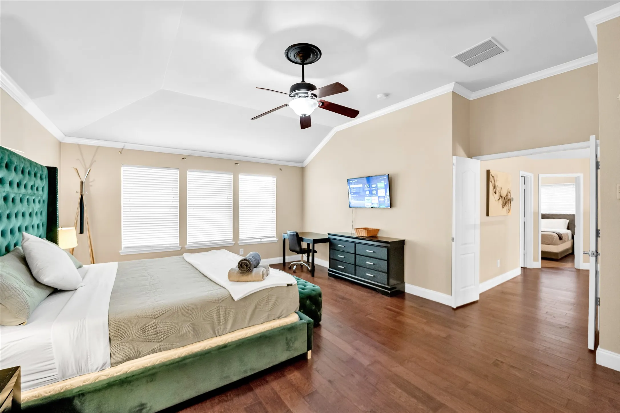 Vaulted ceilings with crown molding, ceiling fan, wood-finish flooring, and multiple windows with blinds