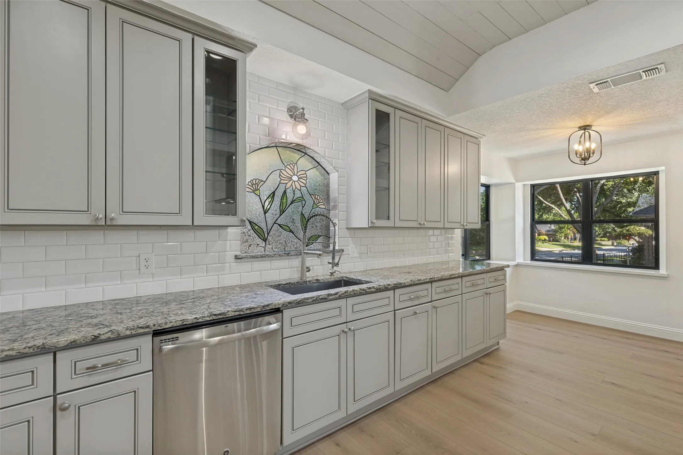 Kitchen with Stained Glass Window over the  Stainless Steel Farm Sink and Stainless Dishwasher, looking towards the Breakfast Nook with Nice Windows with a Lovely View of the Neighborhood