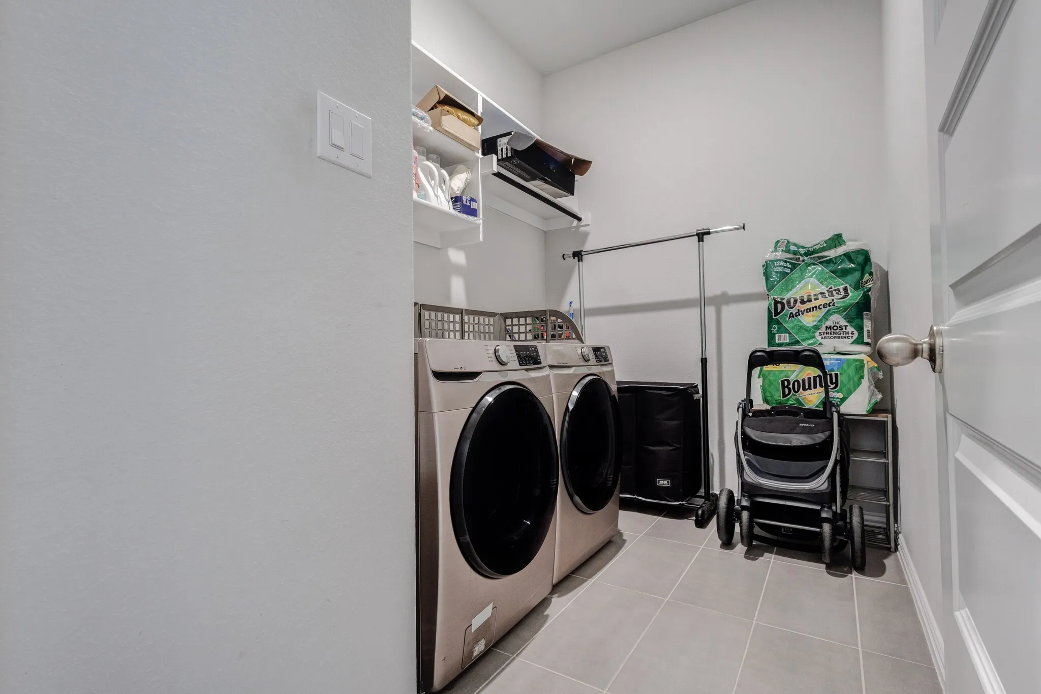 Laundry room with tile flooring, built-in shelving, and a paneled door
