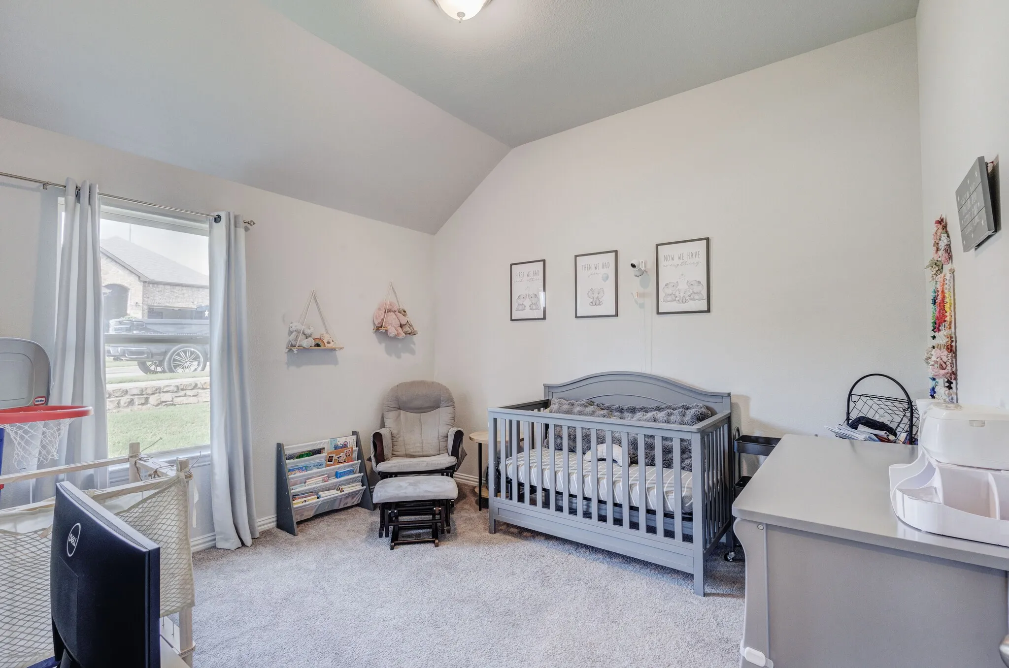 Vaulted ceiling room with light-toned wall paint and neutral carpeting