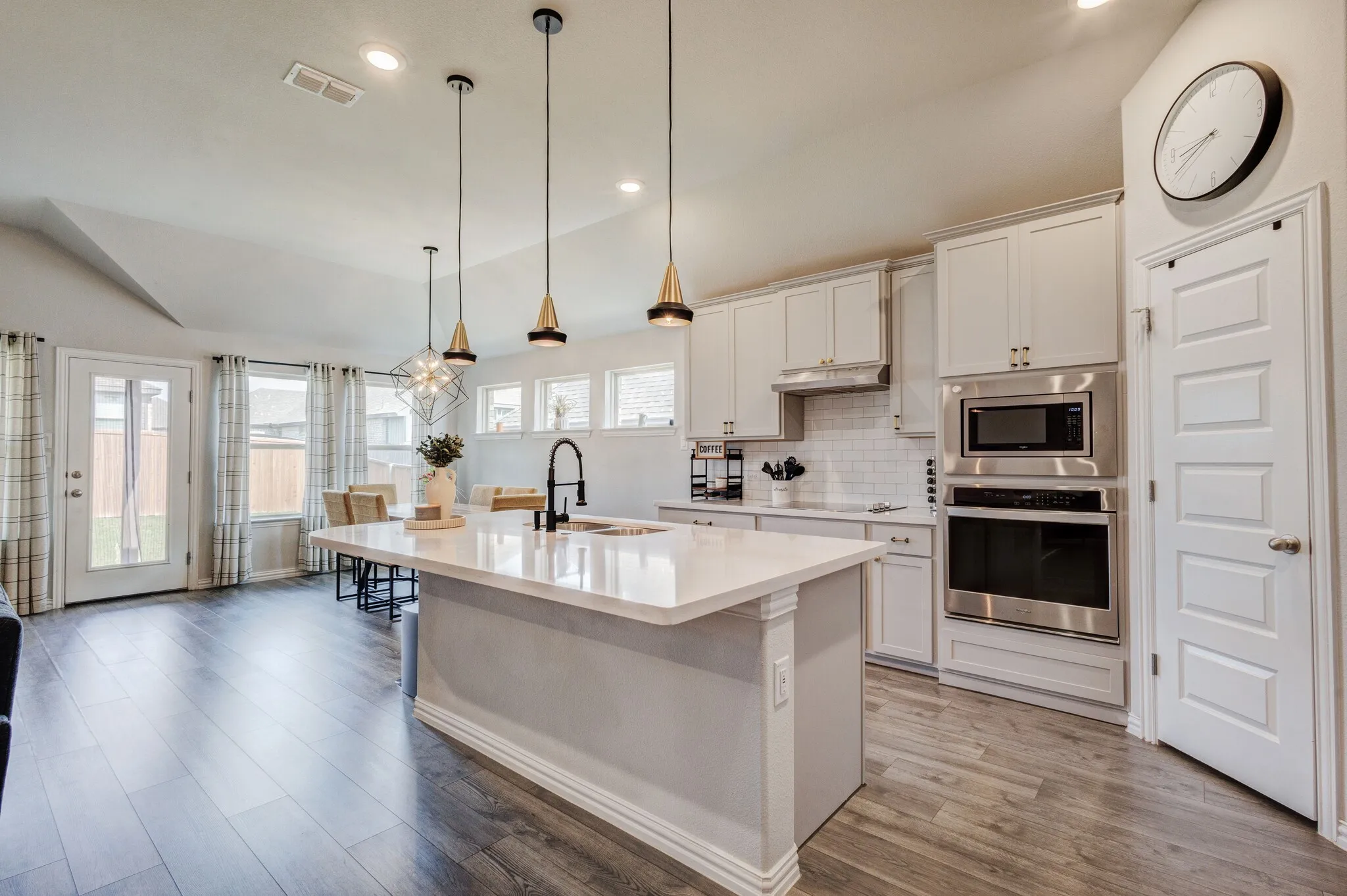 Kitchen featuring stainless steel appliances, white cabinetry, a large center island, pendant lighting, and wood-finish flooring