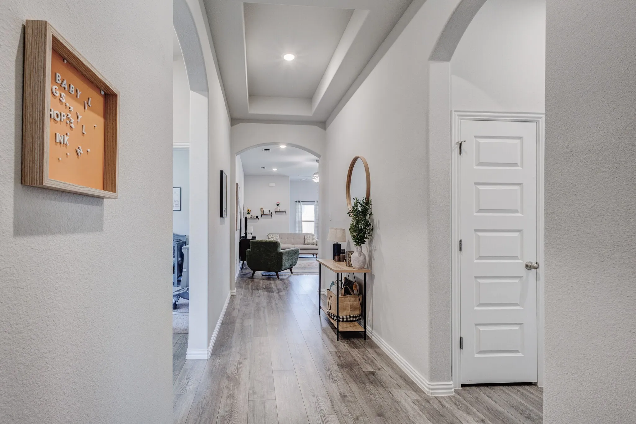 Archway transitions to living spaces, coffered ceiling detail, recessed lighting, wood-finish flooring, and a five-panel interior door