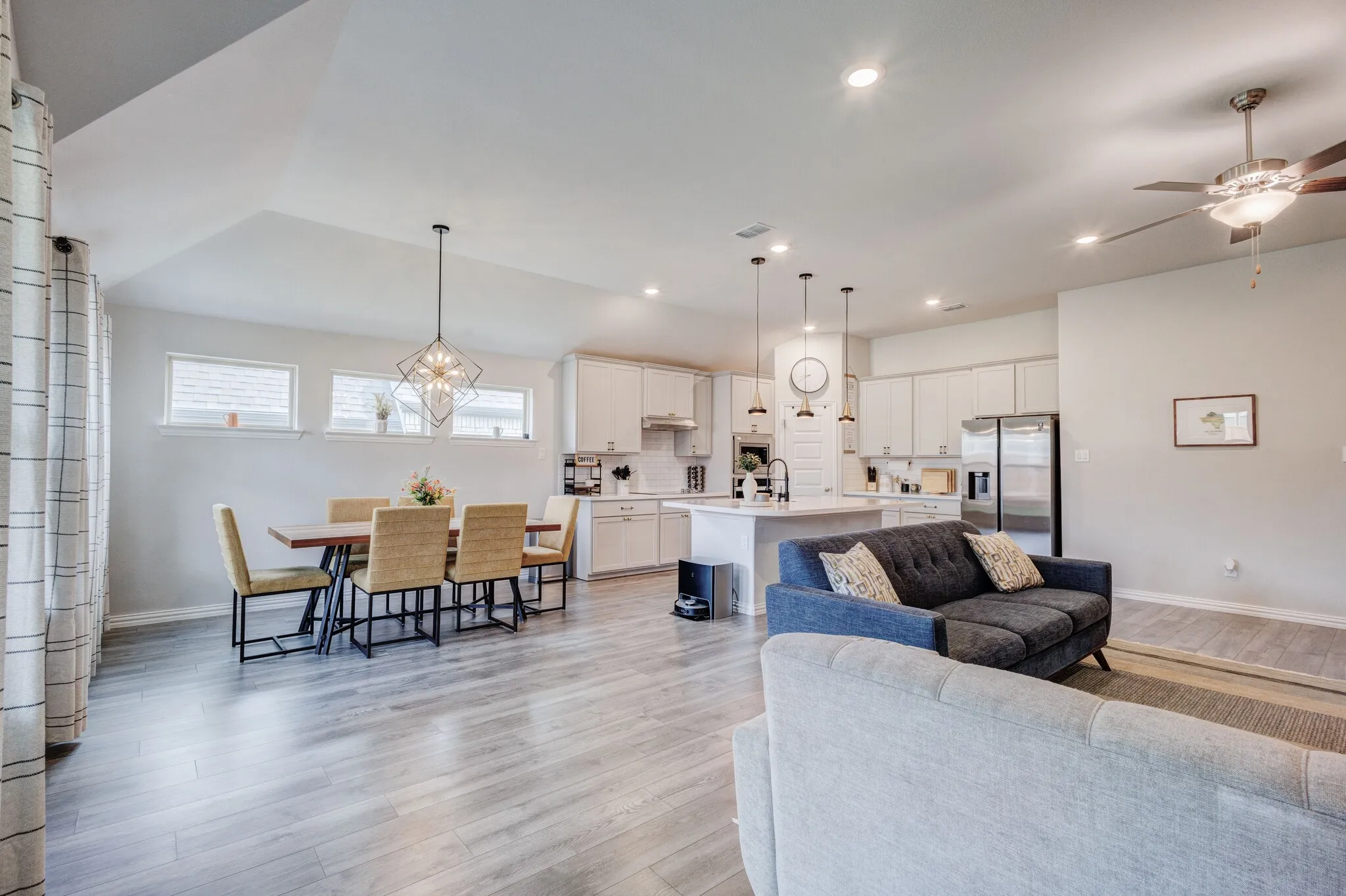 Open-concept living space with wood-finish flooring, vaulted ceilings, and recessed lighting