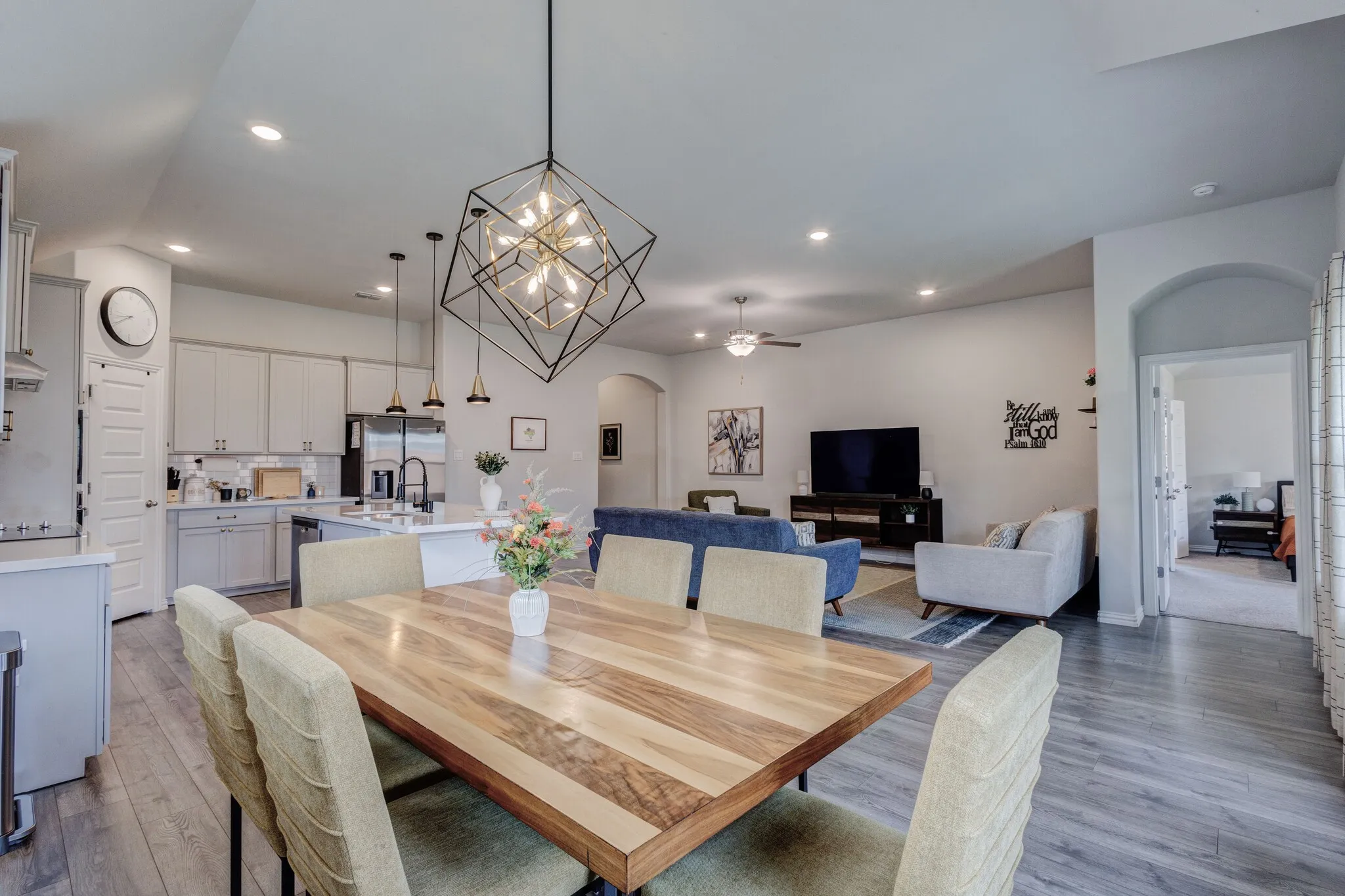 Open-concept living space featuring wood-finish flooring, recessed lighting, and a contemporary geometric chandelier