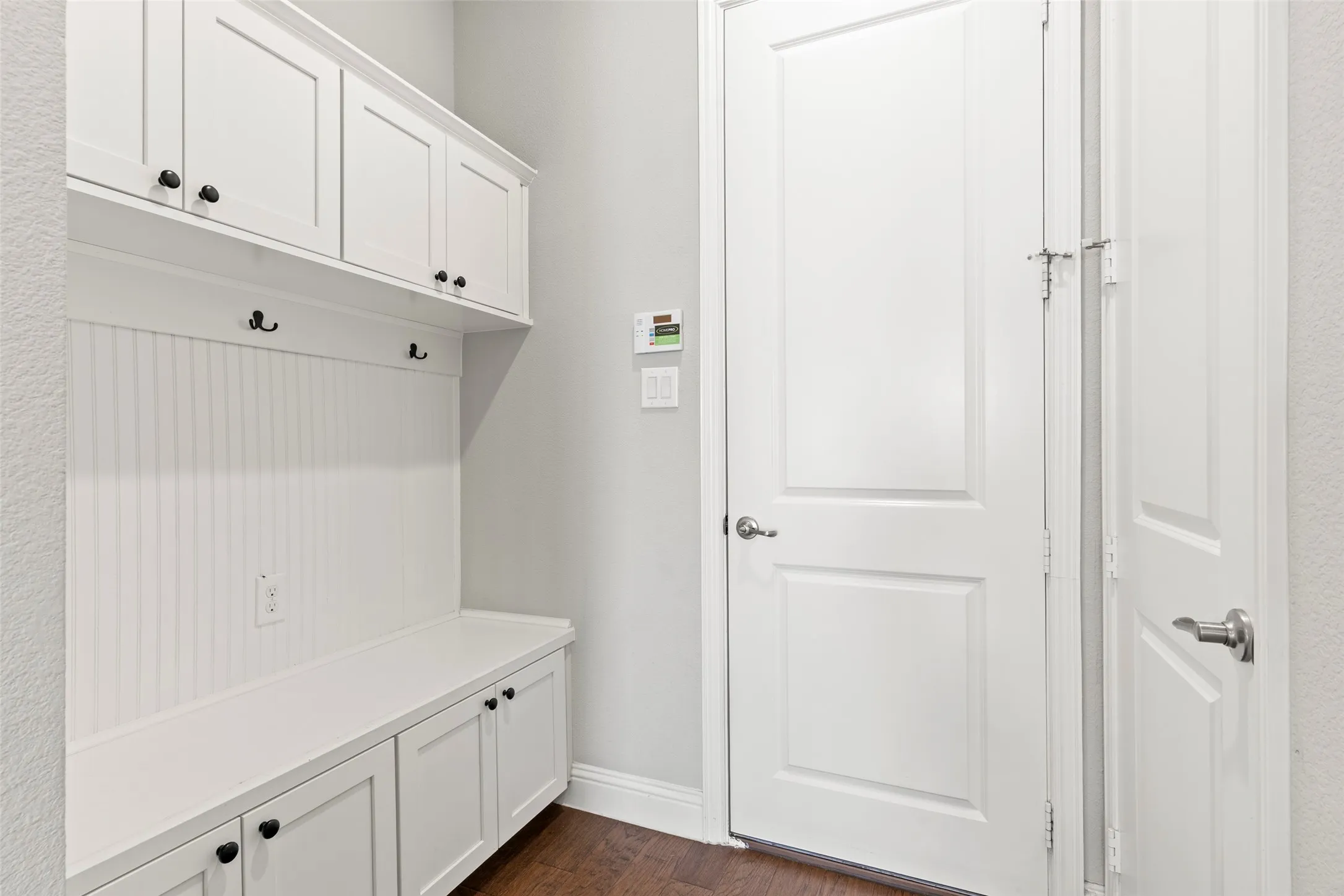 Built-in white cabinetry, integrated bench seating, beadboard paneling, and dark wood-finish flooring