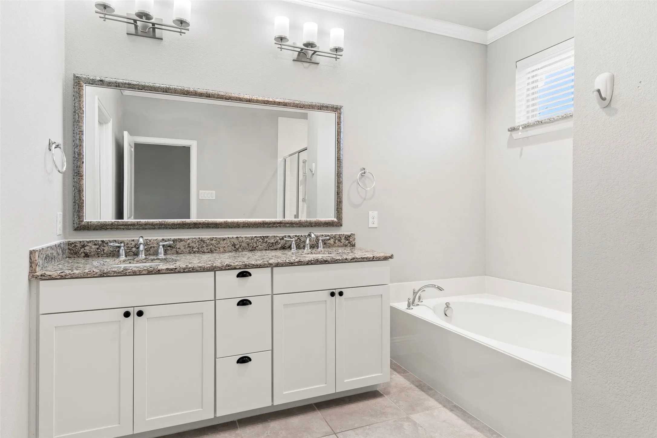 Spa-inspired primary bathroom featuring a white vanity with multiple storage drawers, granite-topped countertop, and polished nickel hardware