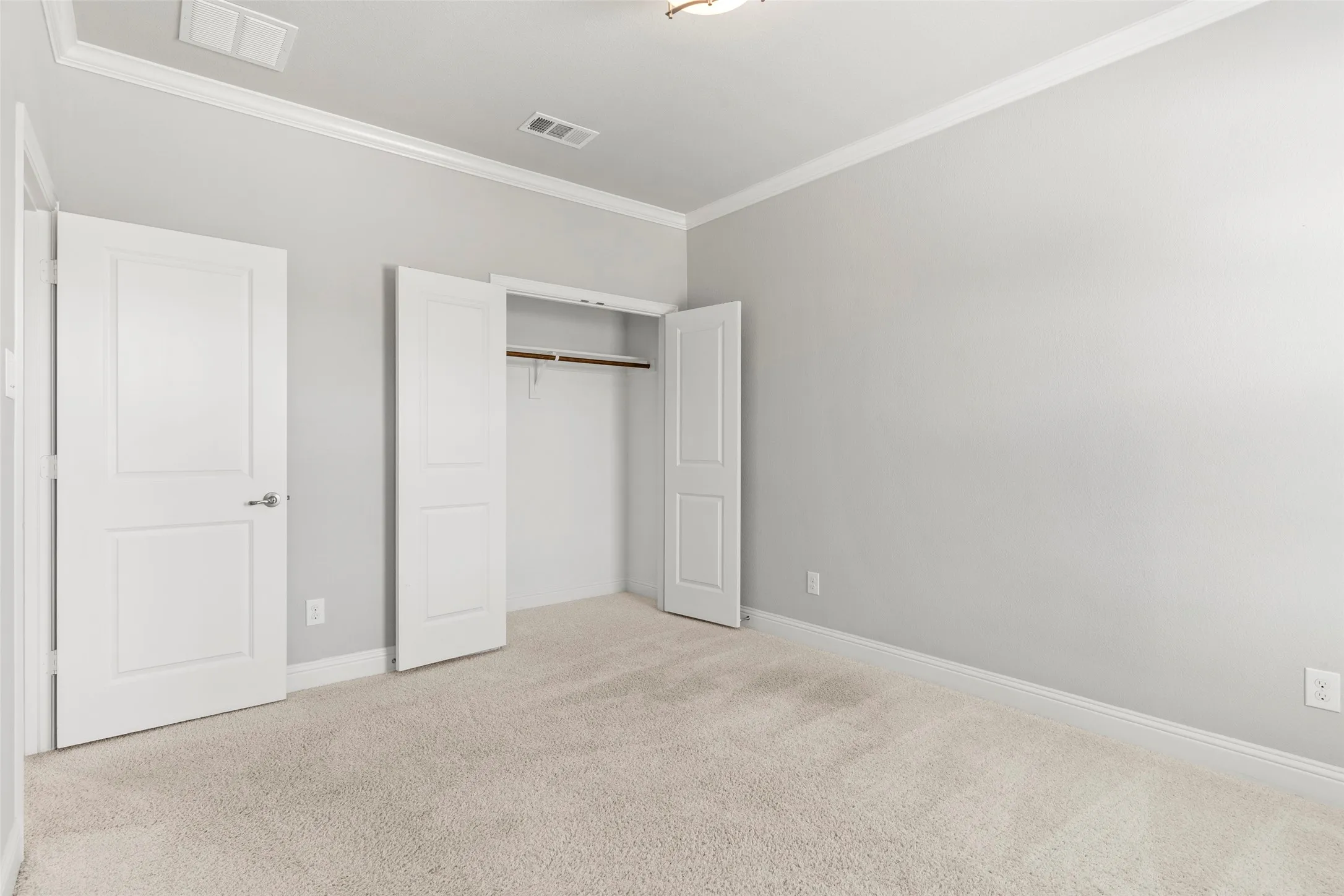 Bright, neutral bedroom featuring neutral carpet flooring, dual closets with white panel doors, and abundant natural light from recessed ceiling fixtures