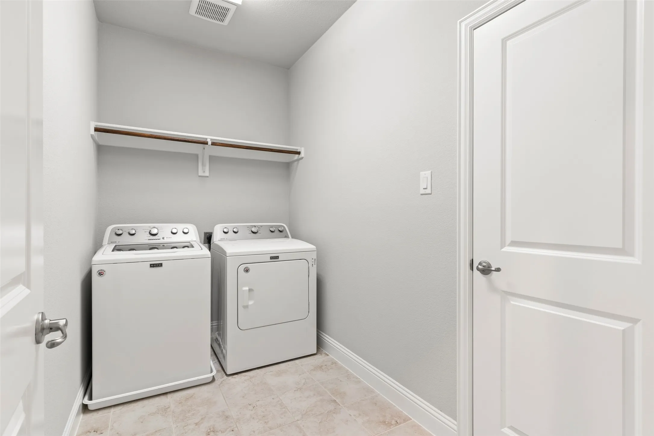 Utility area featuring a built-in shelf with hanging rod, tile flooring, and two panel doors