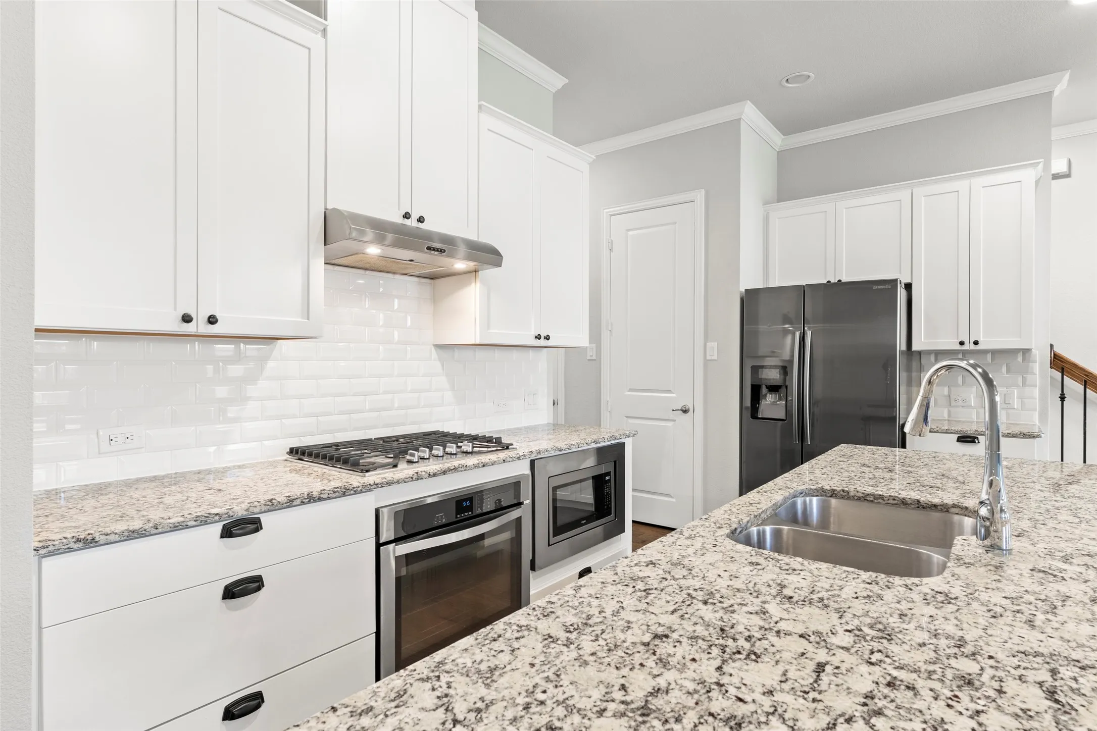 Kitchen featuring white shaker cabinetry, speckled countertops, stainless steel appliances, a gas cooktop, and a subway tile backsplash