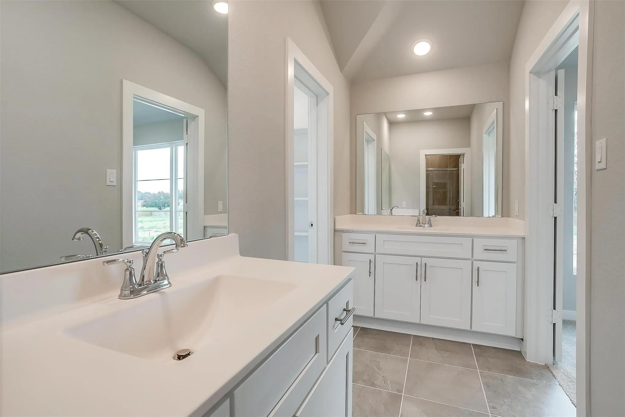 Dual vanity with white cabinetry, polished chrome fixtures, and integrated sinks
