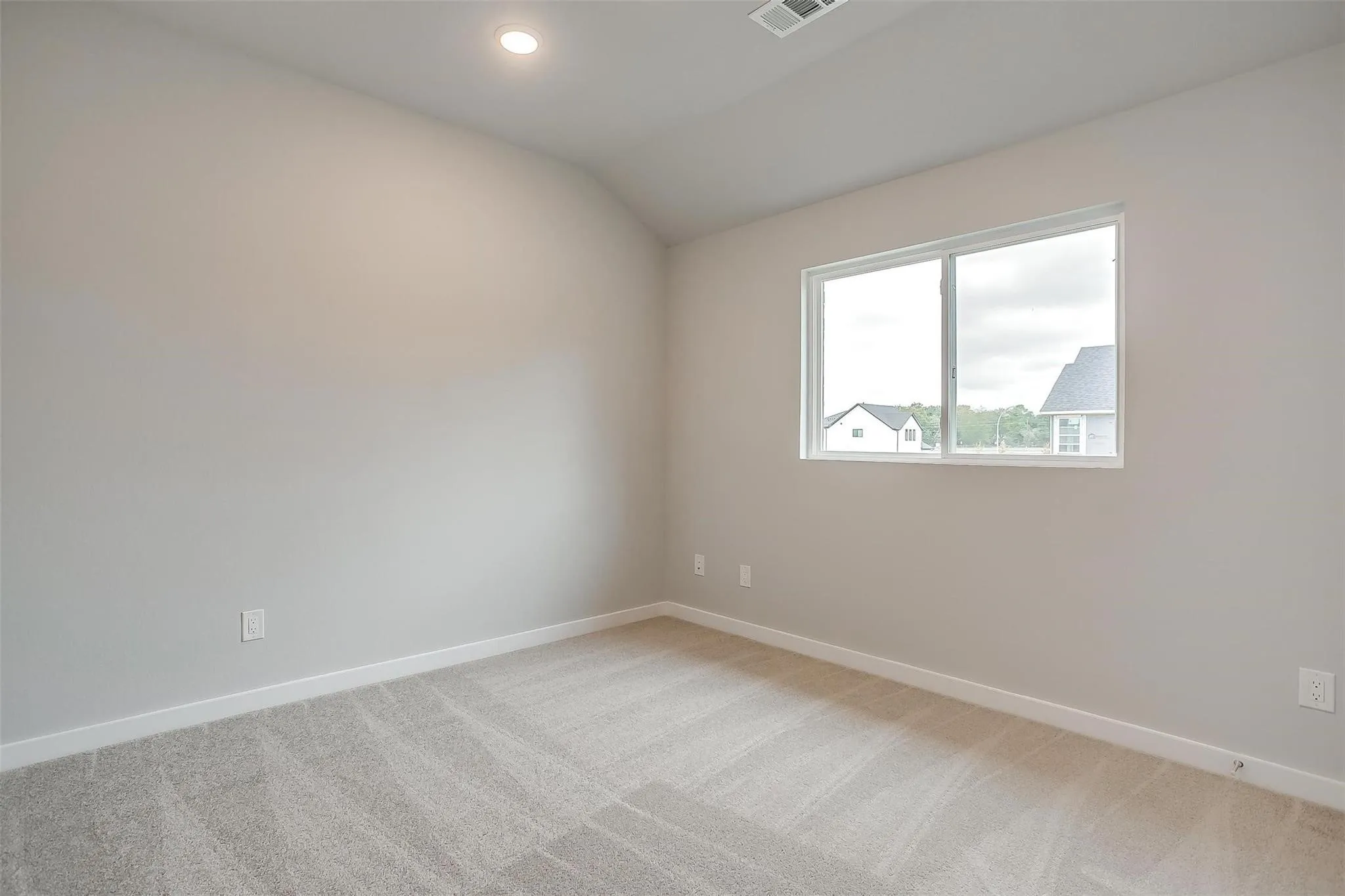 Light gray wall paint, recessed ceiling lighting, light gray carpet, white trim, and a white-framed window