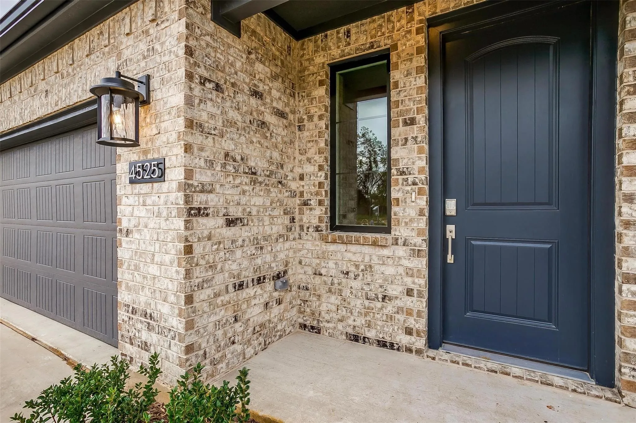 Brick exterior with dark gray garage door, arched front entry door, and vertical accent window