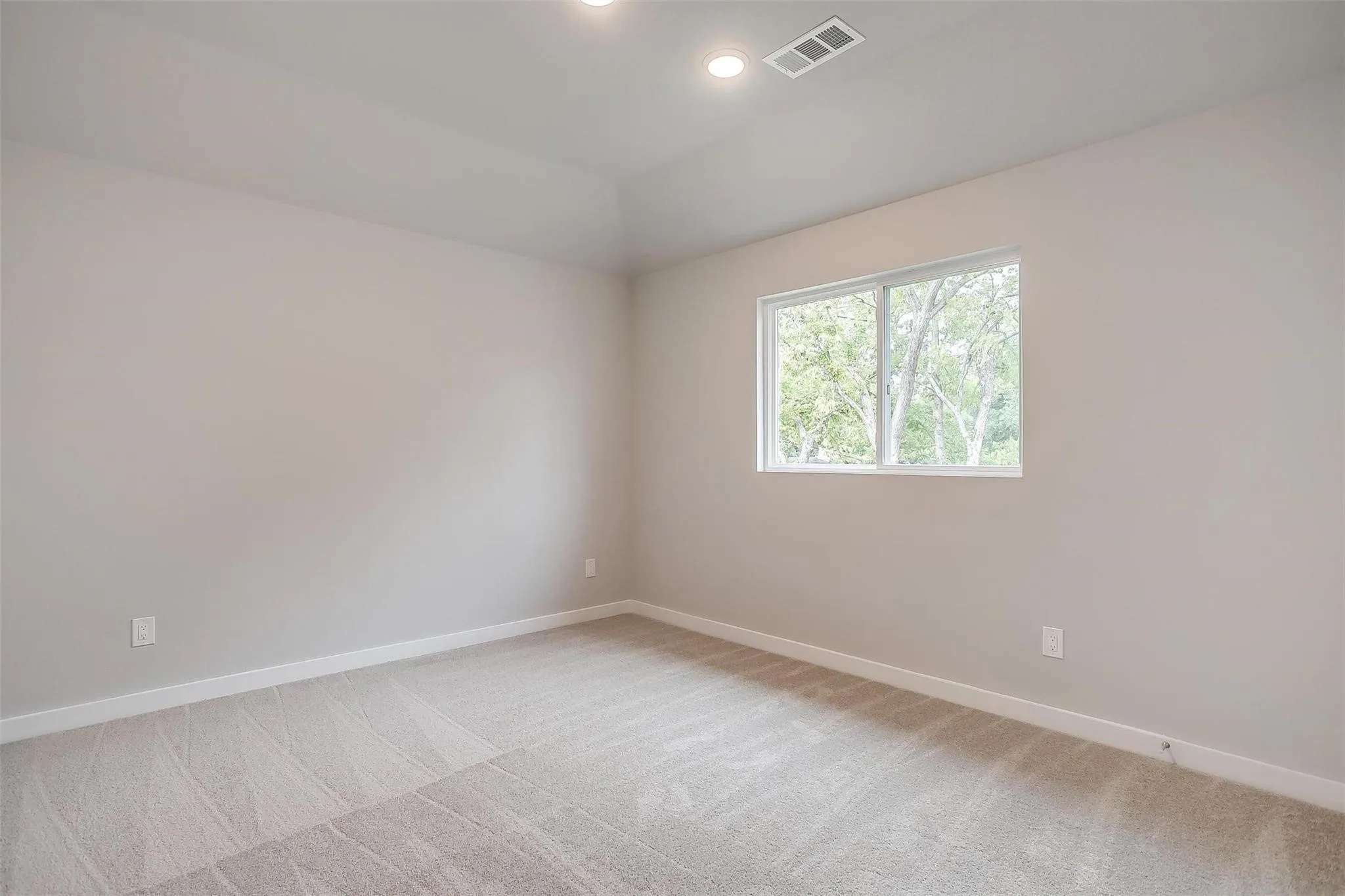 Tray ceiling with recessed lighting, carpeted flooring, and a large window