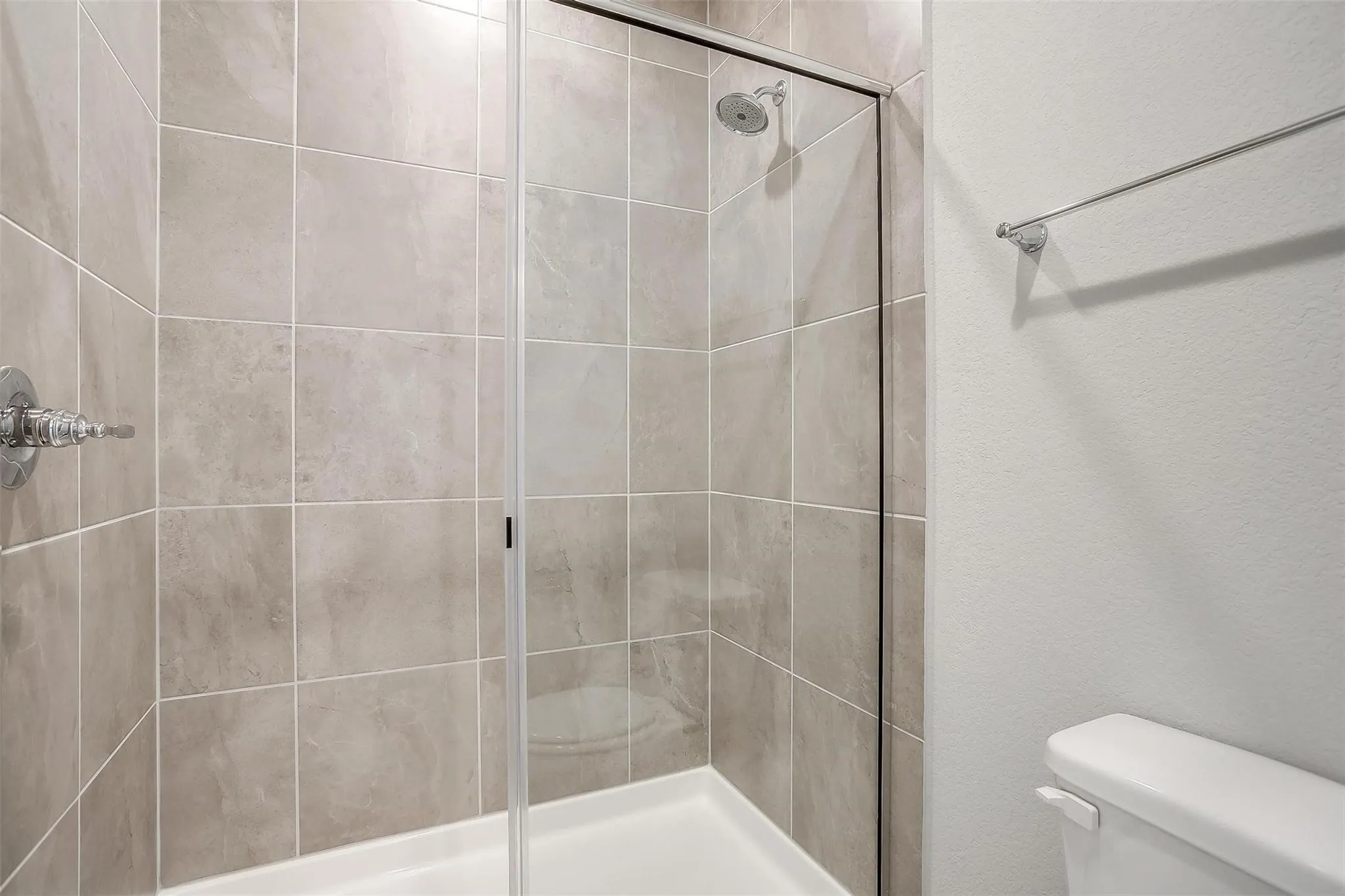 Tiled shower enclosure with a glass door and chrome fixtures