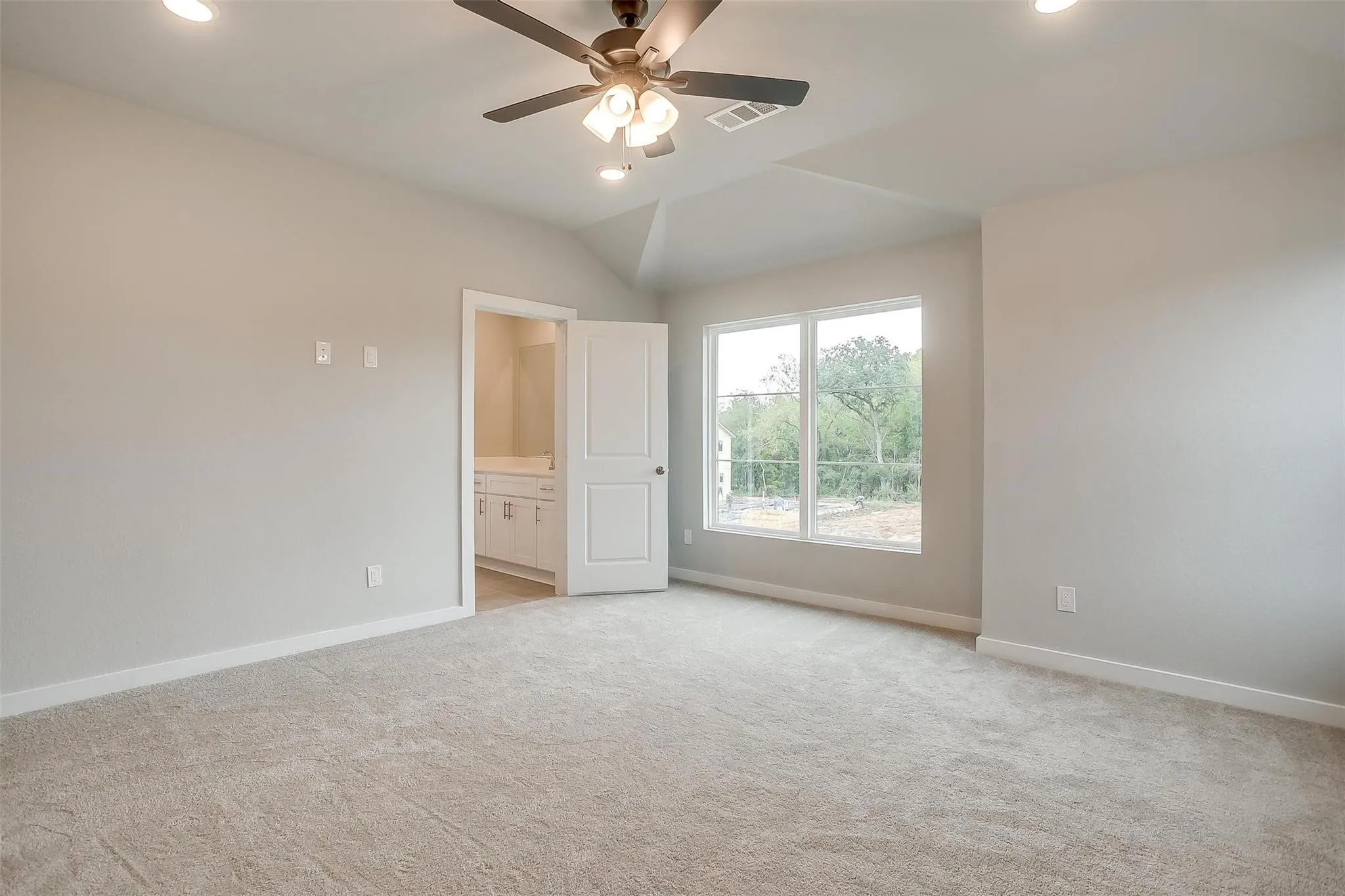 Carpeted room with vaulted ceiling and recessed lighting