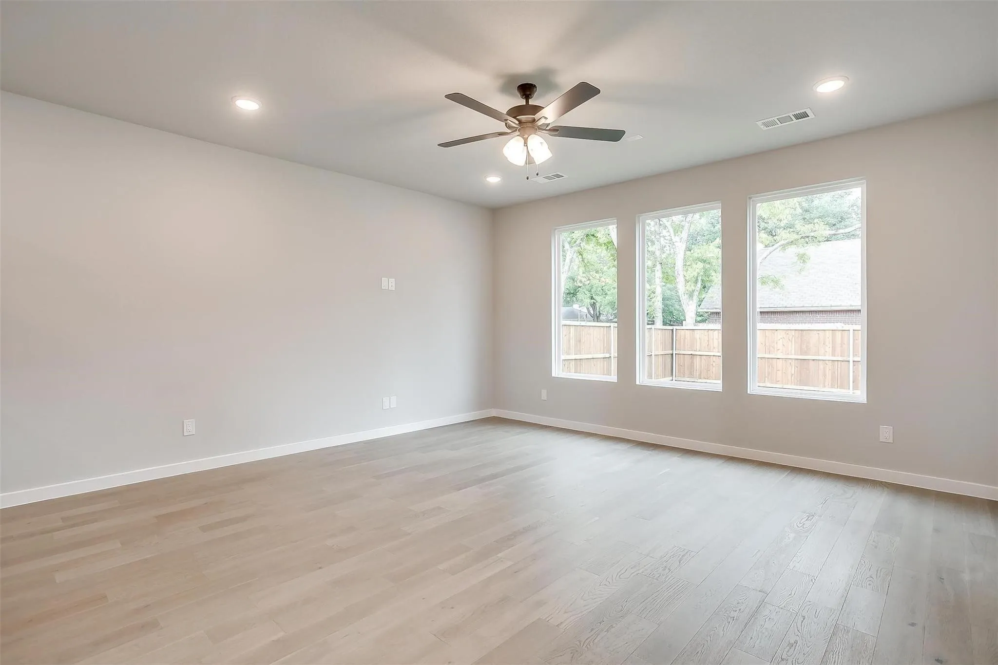 Spacious room featuring light wood-finish flooring, recessed lighting, and a ceiling fan