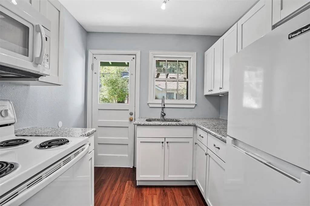 Kitchen featuring white cabinetry, granite-style countertops, wood-finish flooring, and a glass-paneled exterior door