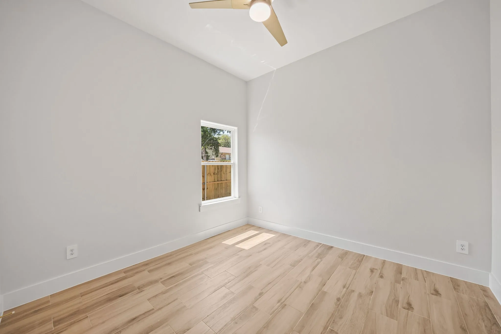 Light wood-finish flooring, white walls, and a contemporary ceiling fan with integrated lighting