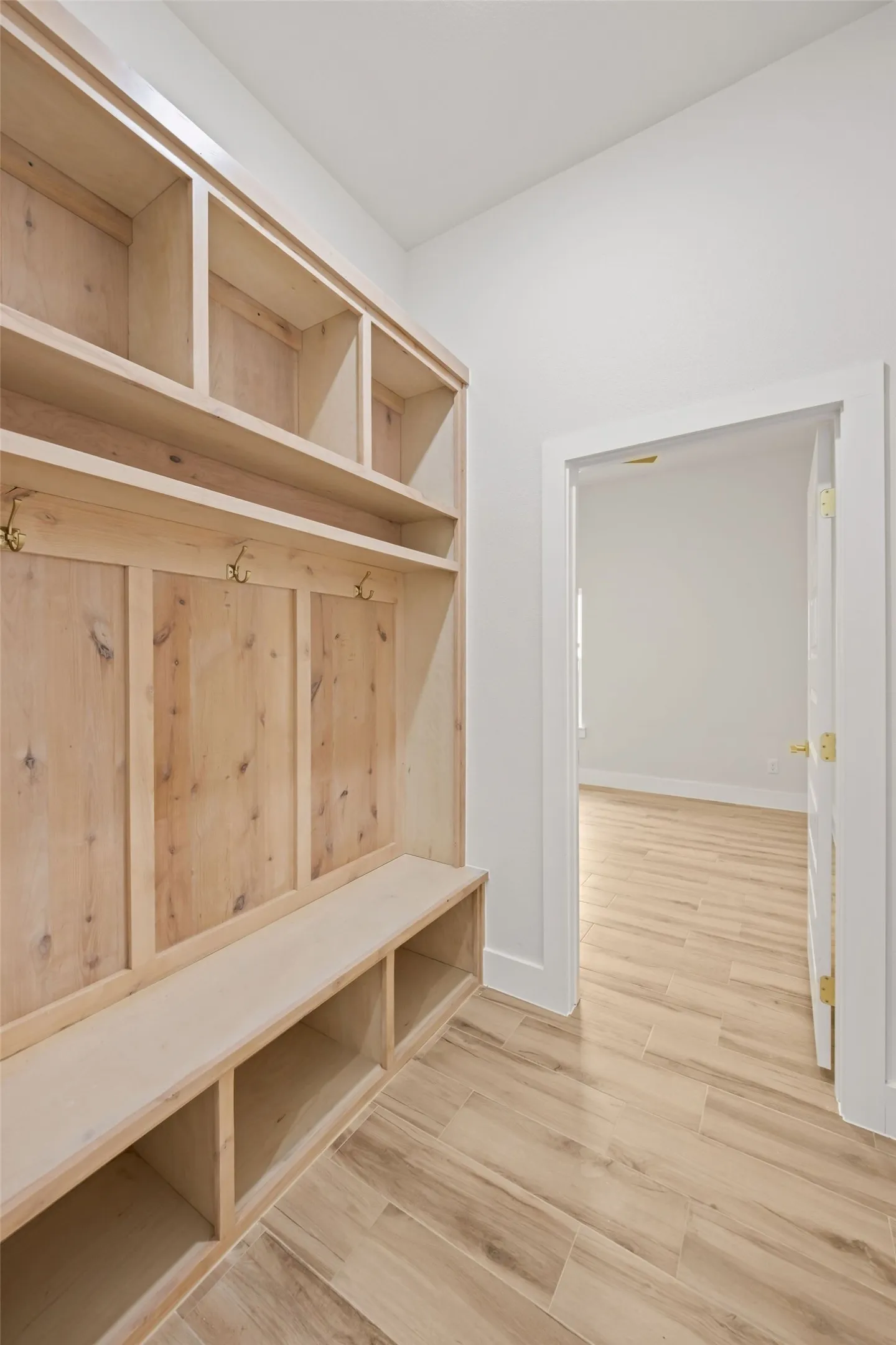 Built-in wood mudroom storage with integrated bench seating, upper cubbies, and coat hooks